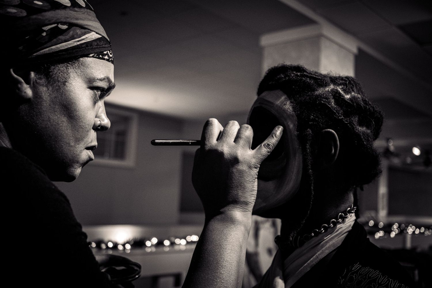 Black and white photo of makeup artist applying cosmetics to a model.
