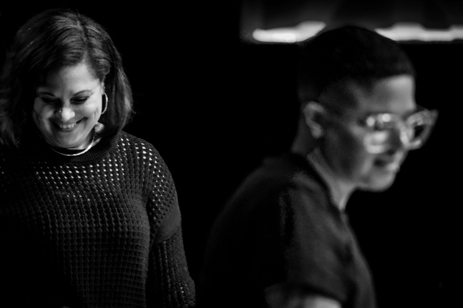 Two performers sharing a candid backstage moment in black and white photography.