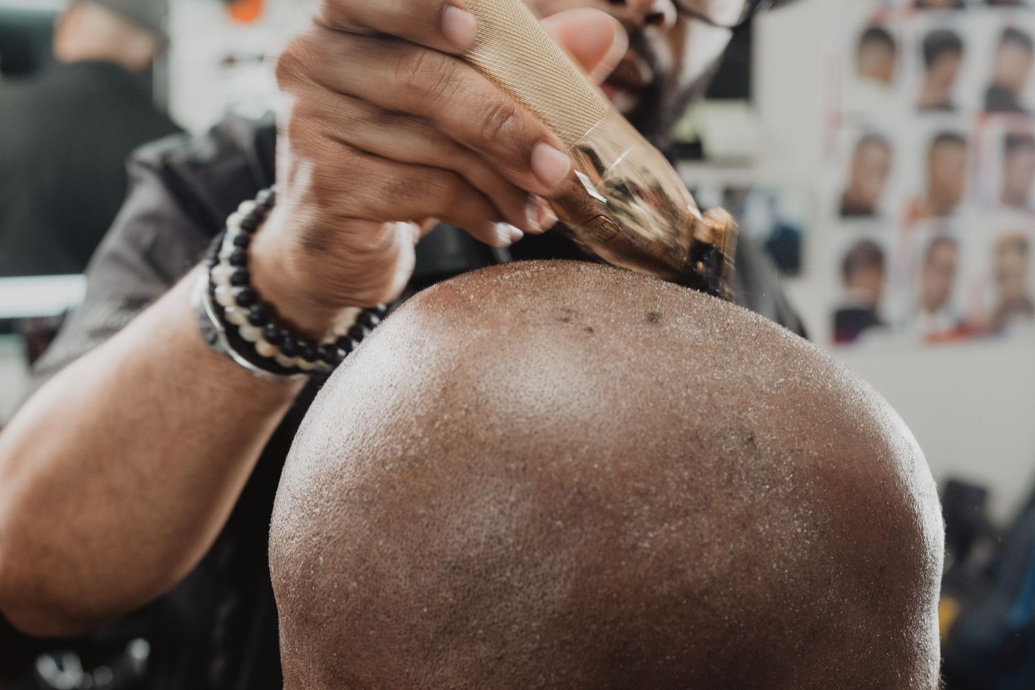 Barber applying hair product to a bald client's head in a barbershop.