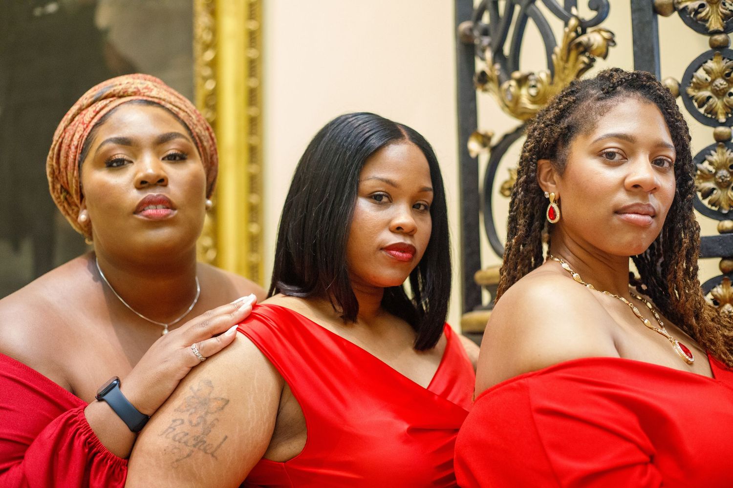 Three women in red dresses posing confidently indoors.