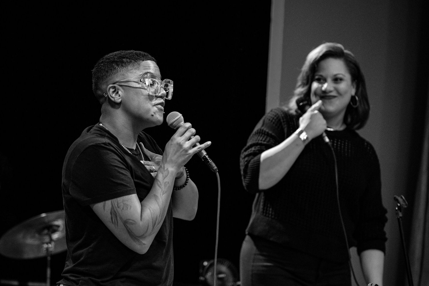 Black and white photo of two singers performing on stage, man holding microphone close.