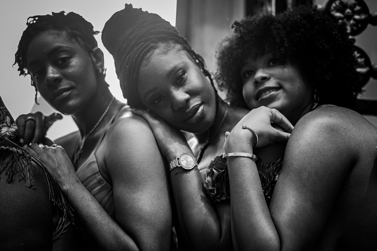 Black and white portrait of three Black women posing together in a close, relaxed group.