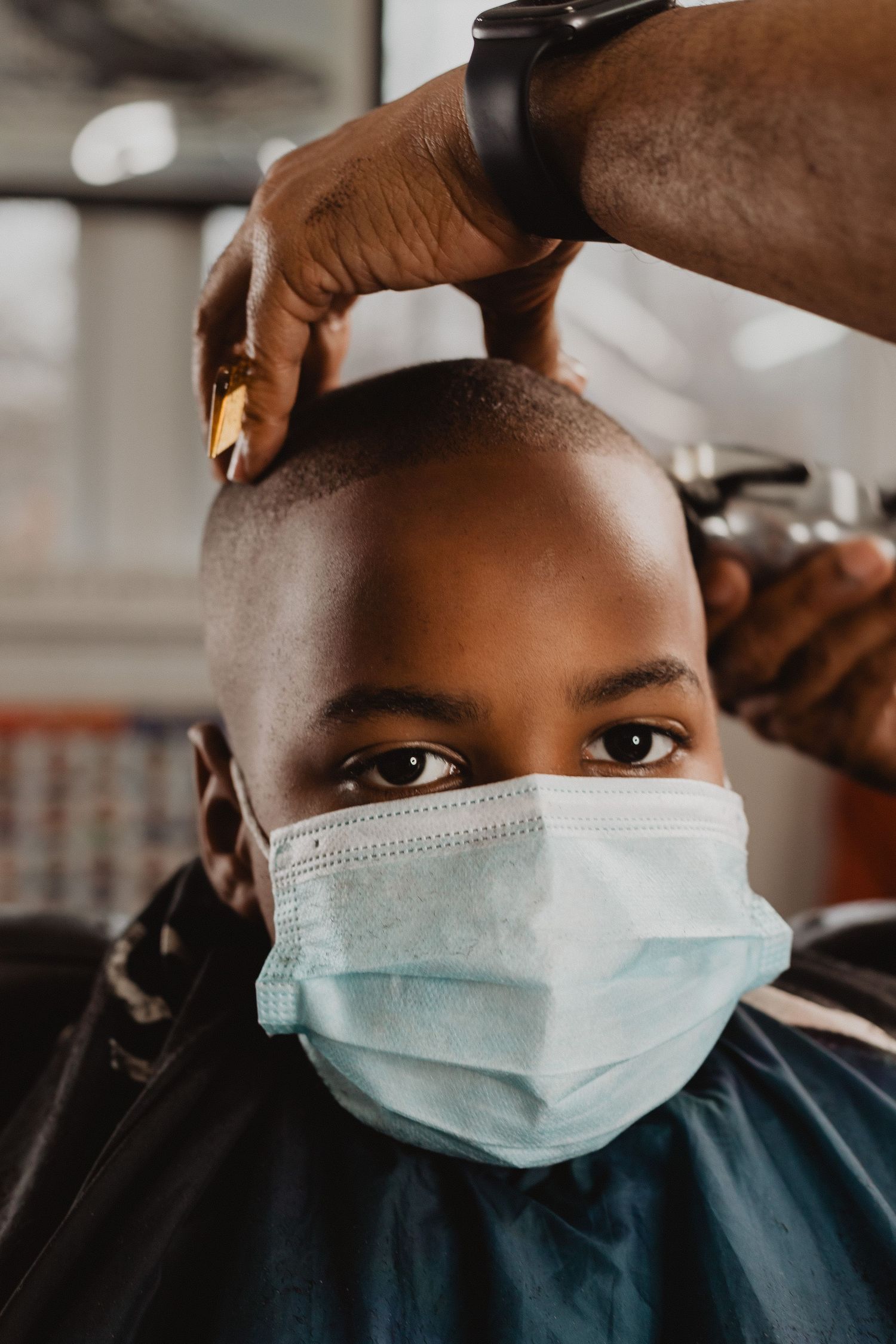 Young boy wearing a face mask getting a haircut at a barbershop during COVID-19.