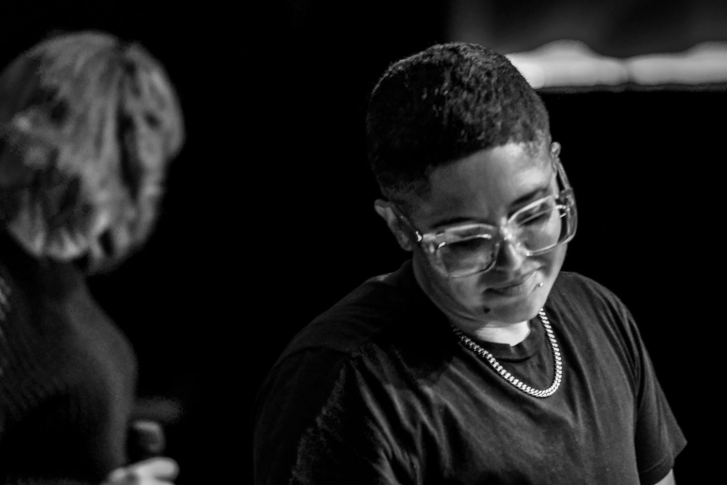 Young male musician with glasses looking down in thoughtful pose in black and white.