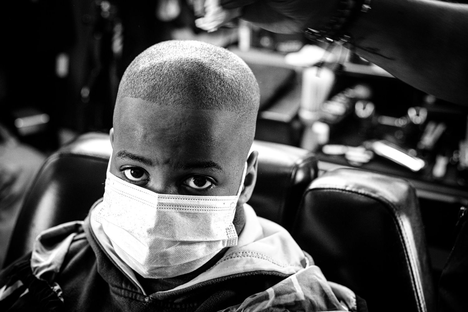 Black and white portrait of a young boy wearing a face mask after a fresh haircut.