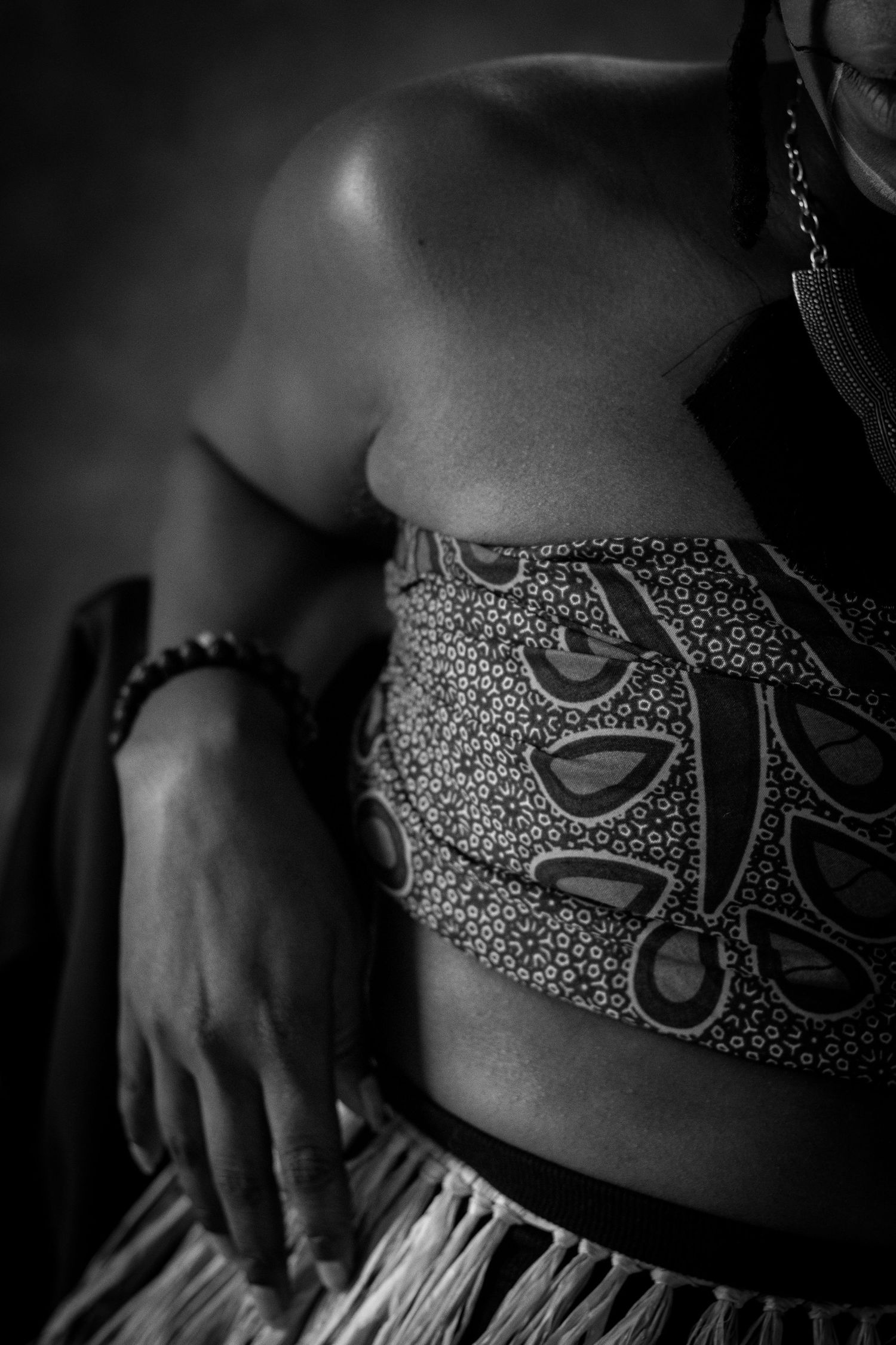 Black and white close-up of woman in patterned African print crop top with beaded bracelet.