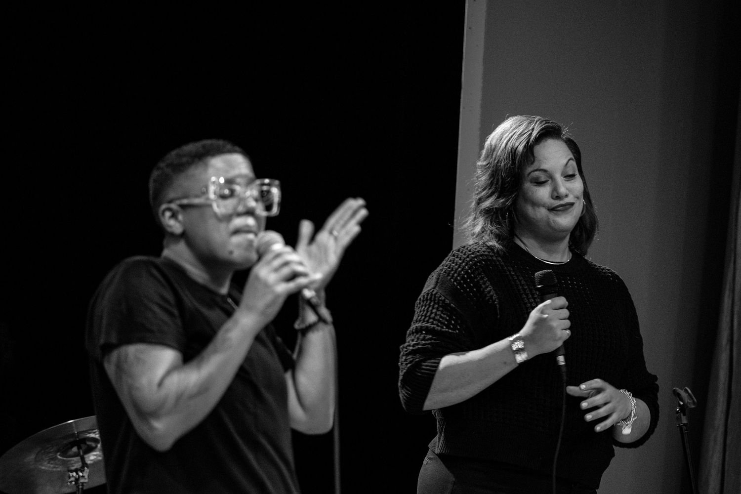 Black and white photo of two singers performing on stage with microphones.
