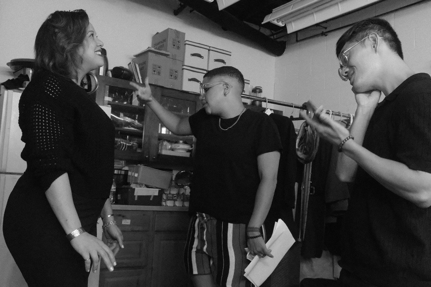 Black and white photo of three musical artists singing and practicing backstage.