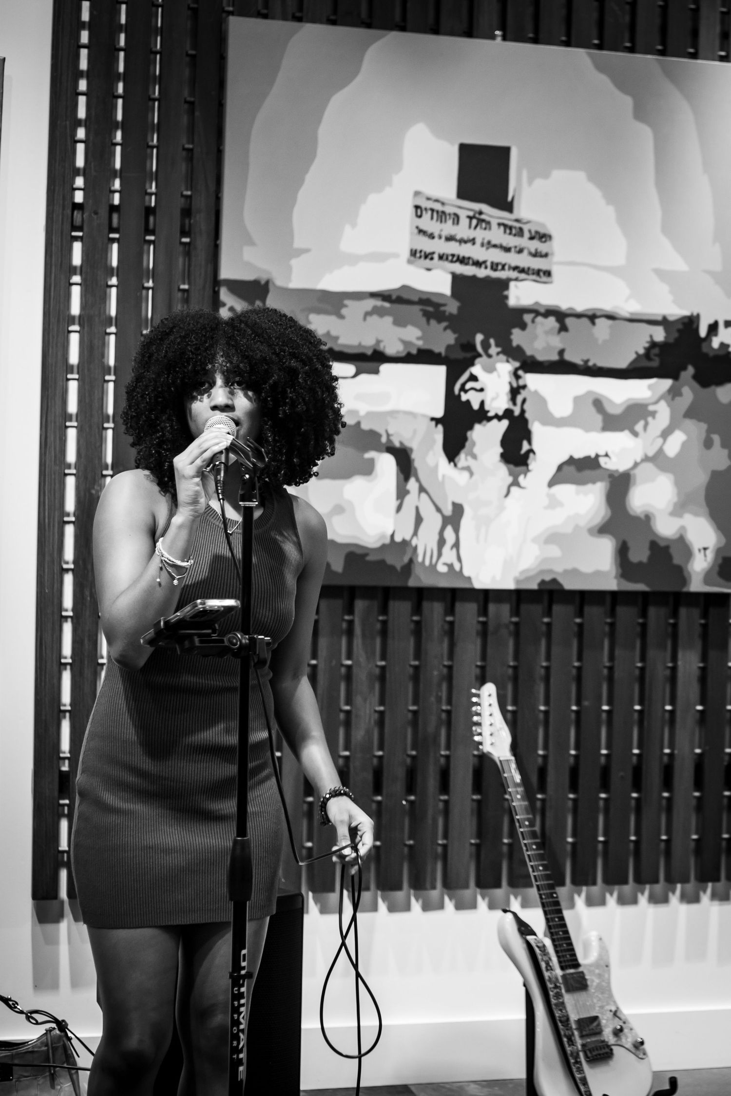 Black and white photo of female vocalist performing in short dress at indoor venue.