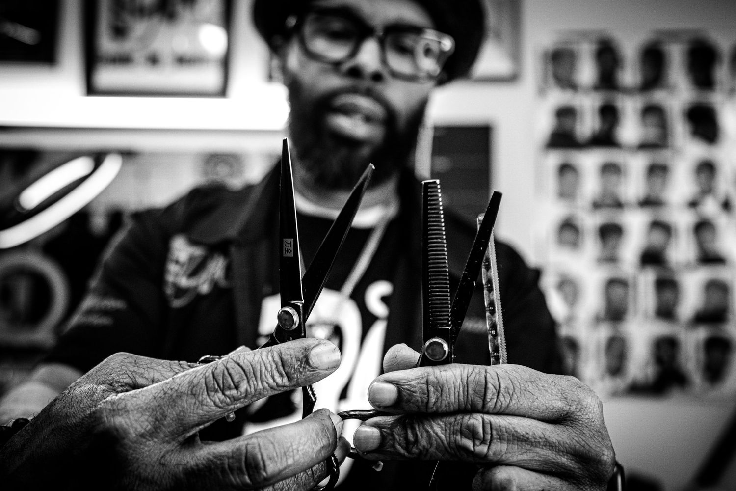 Black and white close-up of a barber holding scissors ready to cut hair in a barbershop.