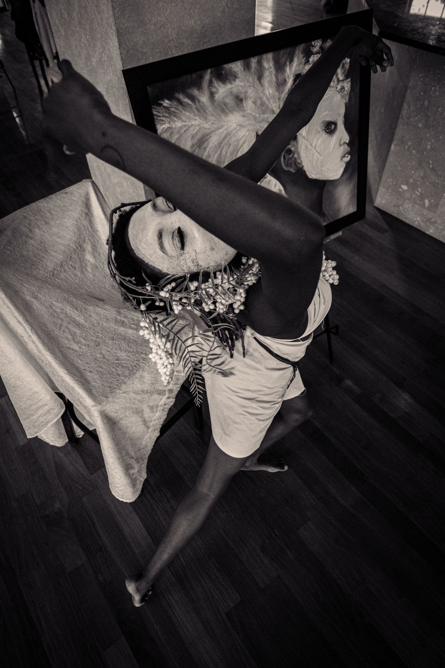 Black and white photo of dancer performing high leg extension near a mirror.
