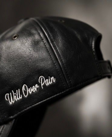 Black leather snapback cap with white embroidered cursive text reading Will Over Pain on the side panel.