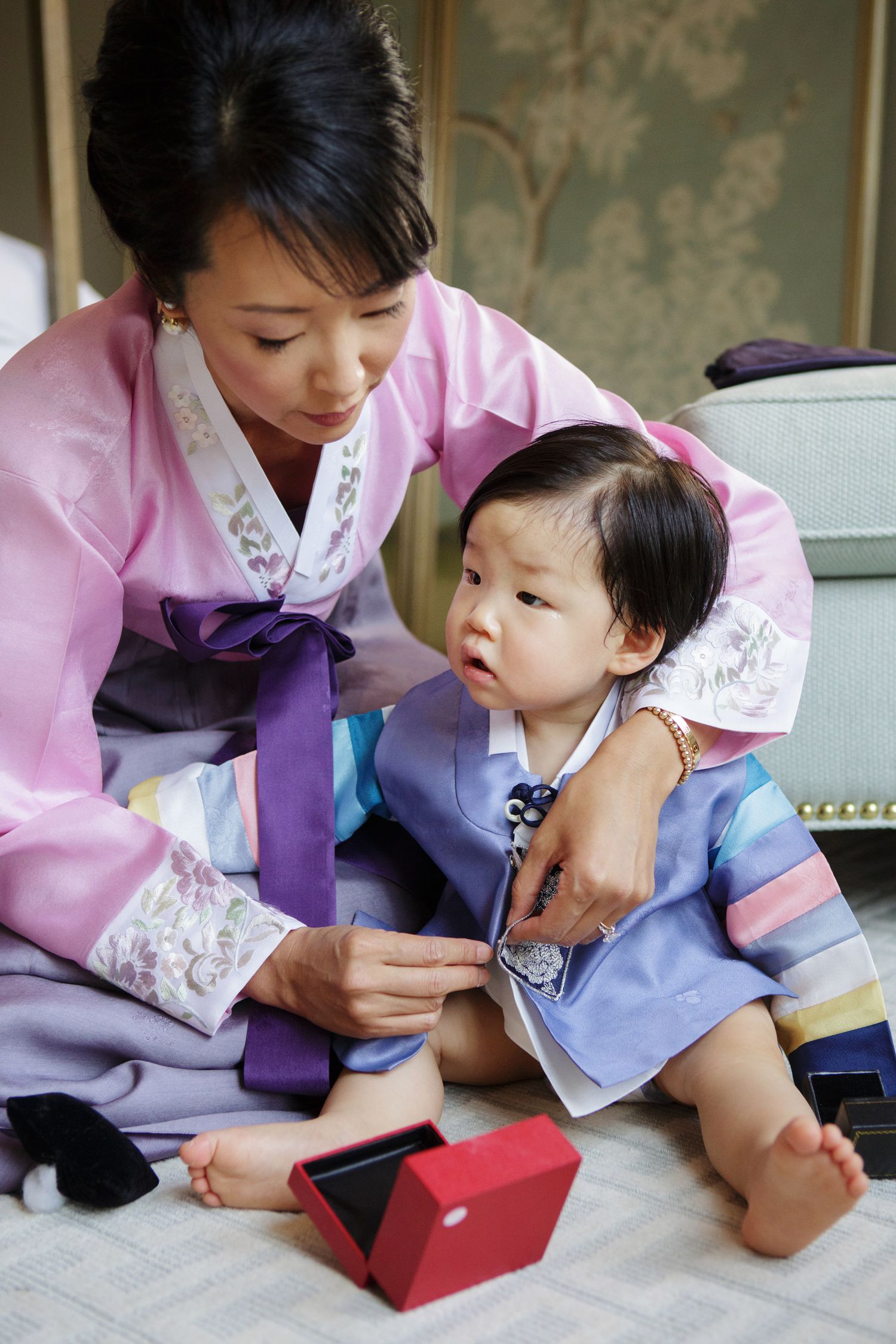 Mother and baby in traditional Korean hanbok attire during a dol first birthday celebration ceremony.