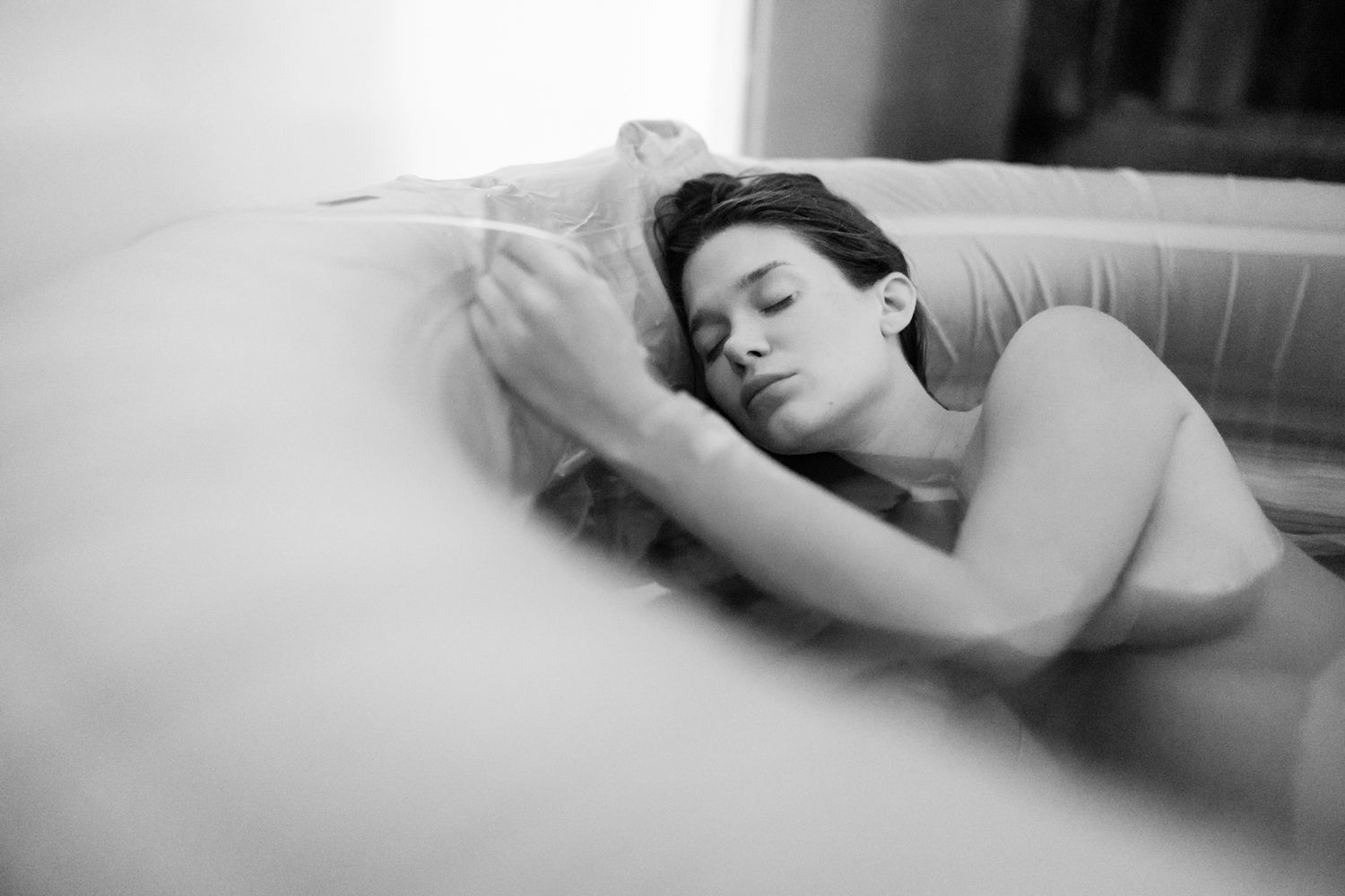Black and white photo of a young woman peacefully sleeping on a soft pillow in bed.