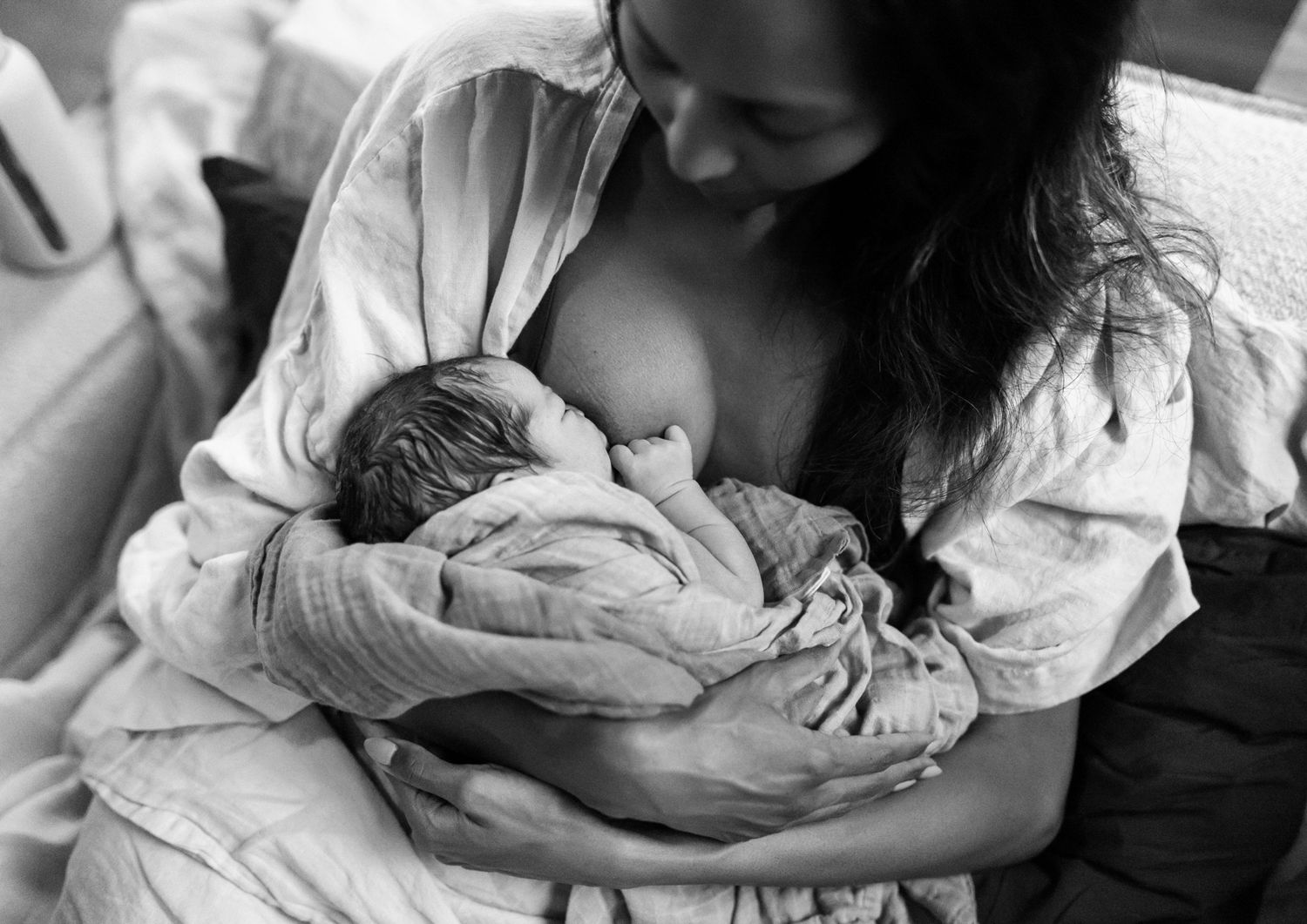 Black and white photo of a mother breastfeeding her newborn baby shortly after birth.