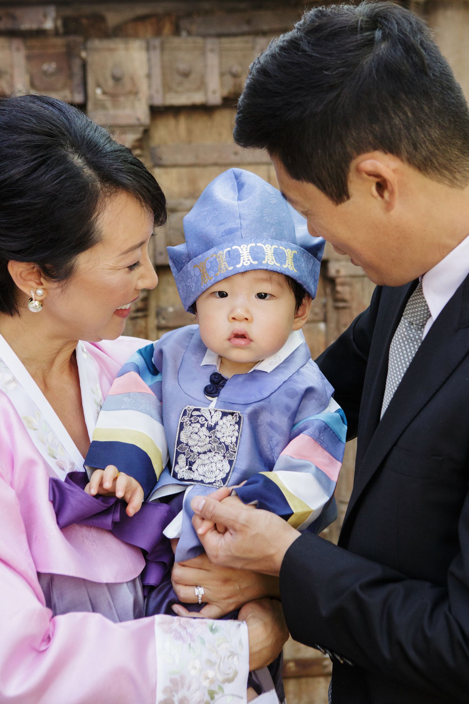 Family with baby dressed in traditional Korean hanbok at first birthday doljabi ceremony.