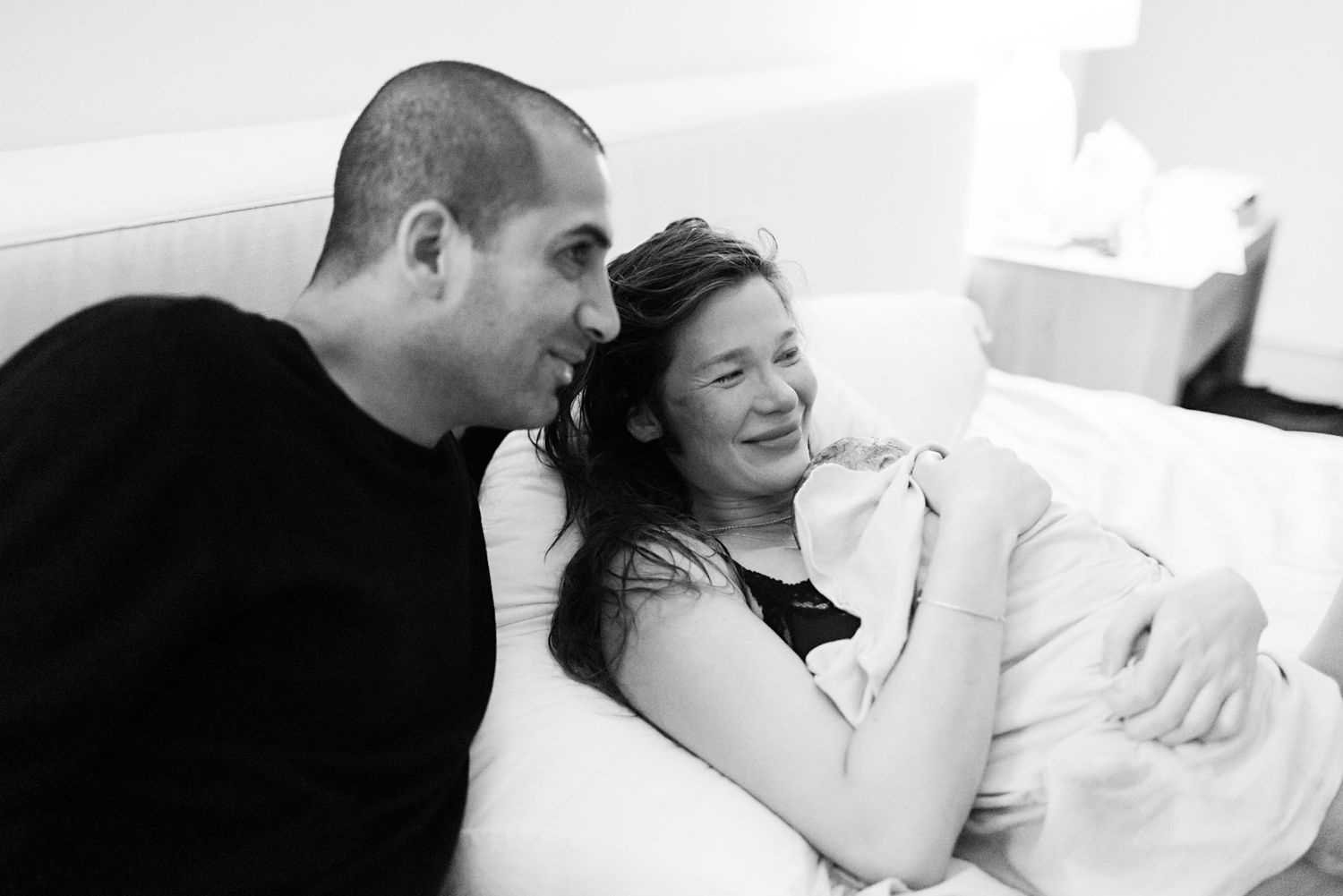 Couple shares a tender moment together on bed during home birth labor process.