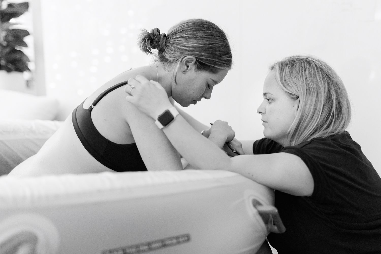 Doula supporting laboring woman during childbirth, black and white birth photography.