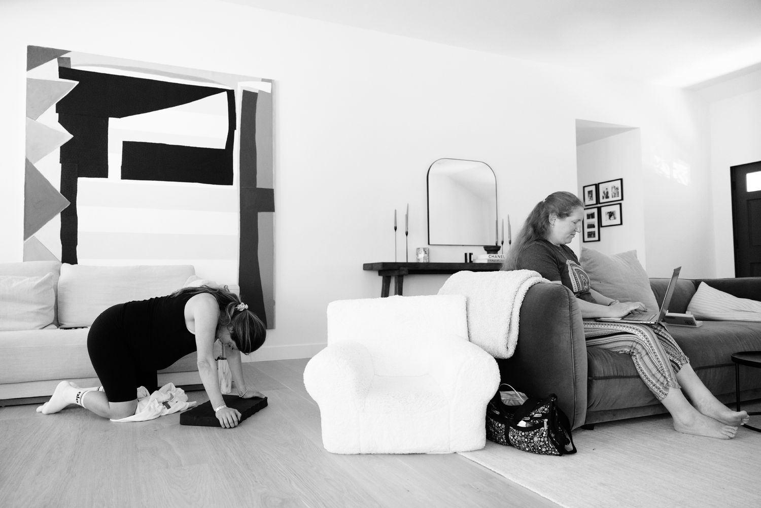 Pregnant woman resting on sofa while support person kneels nearby during early labor.