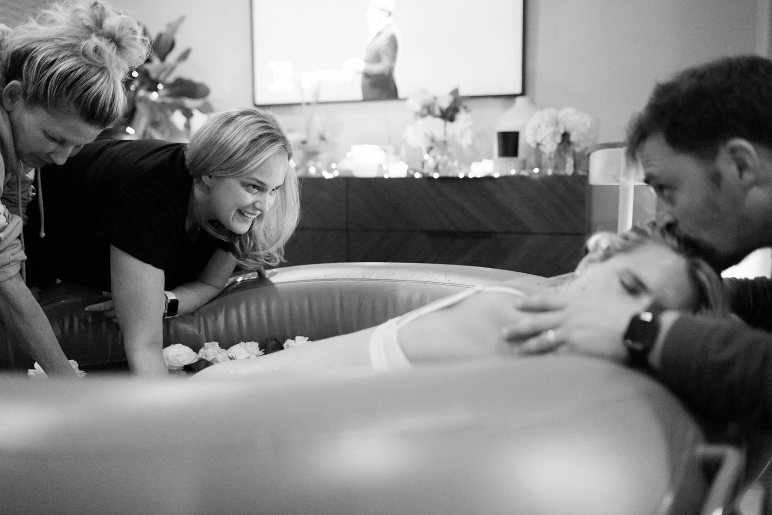 Midwife and partner encouraging woman during water birth labor and delivery.