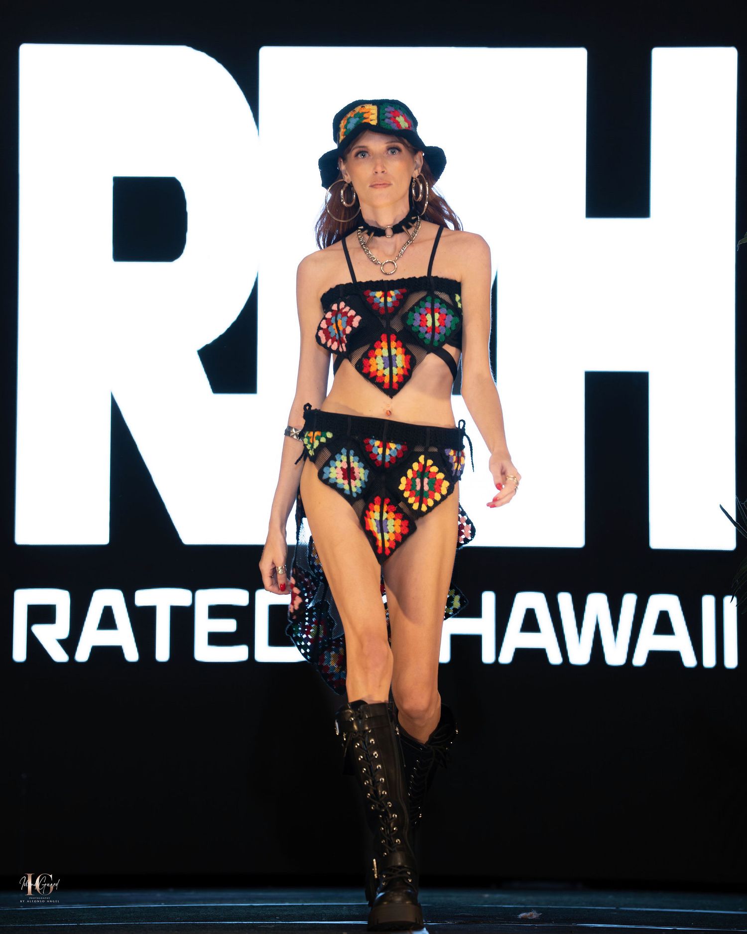 Athletic figure in black swimwear and boots poses against dark background with Ratel Hawaii text display.
