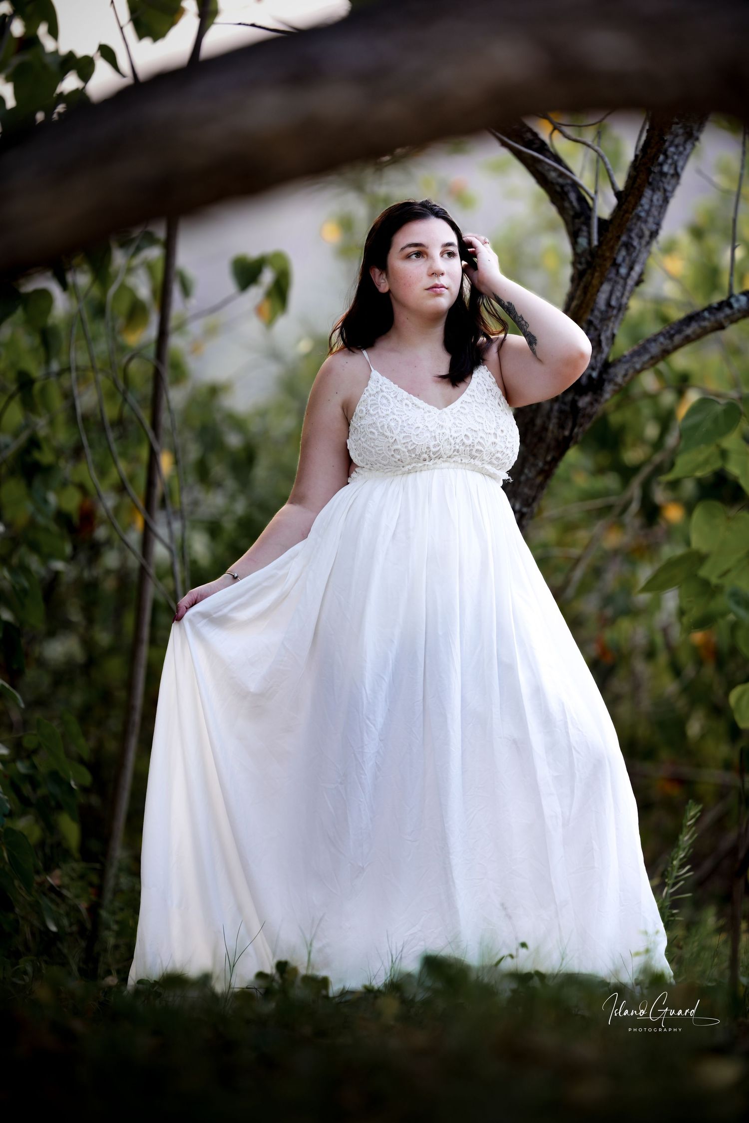 A flowing white wedding gown with sparkly lace bodice and empire waist photographed in a natural garden setting.