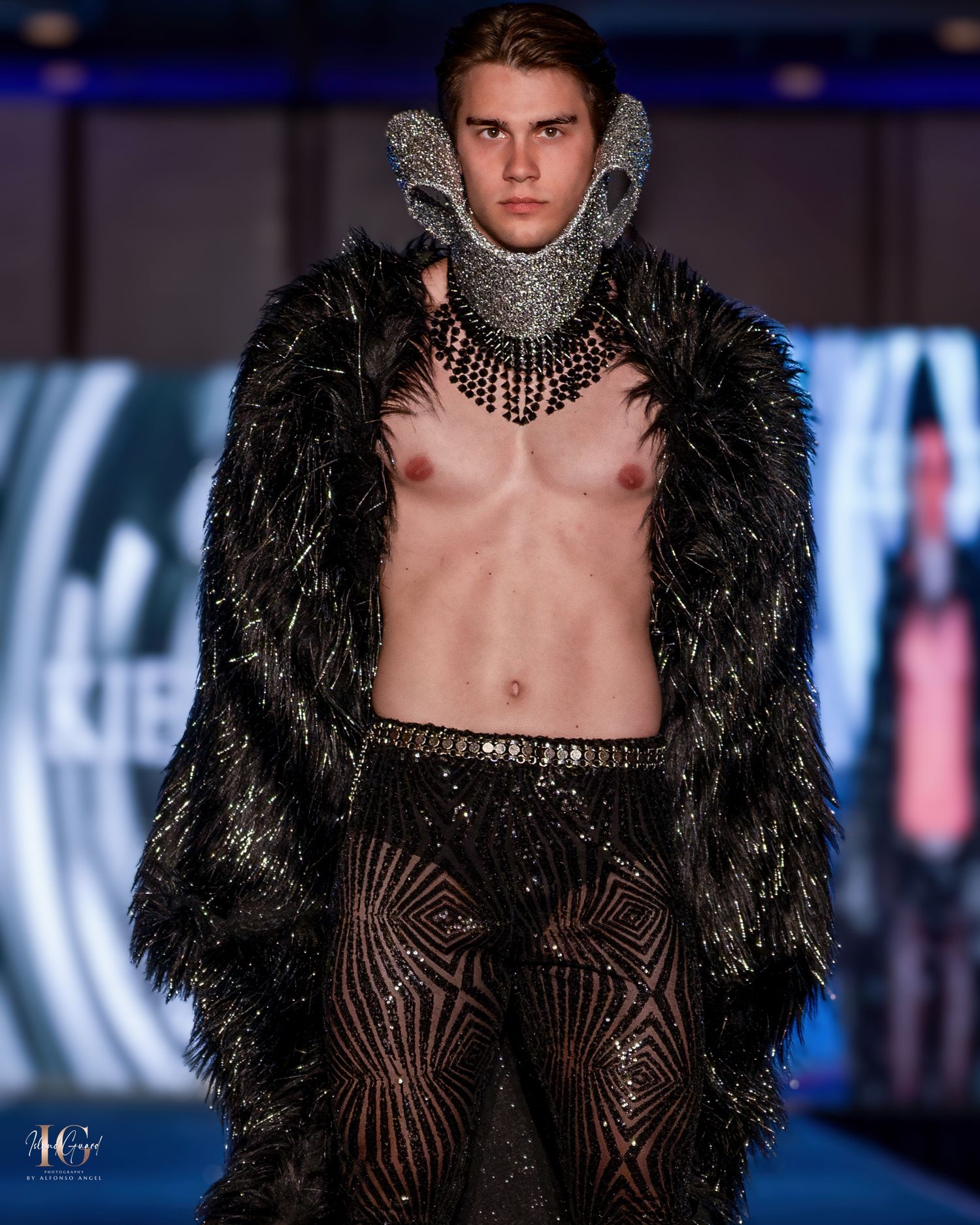 Gothic inspired runway look with feathered coat and ornate metallic collar.