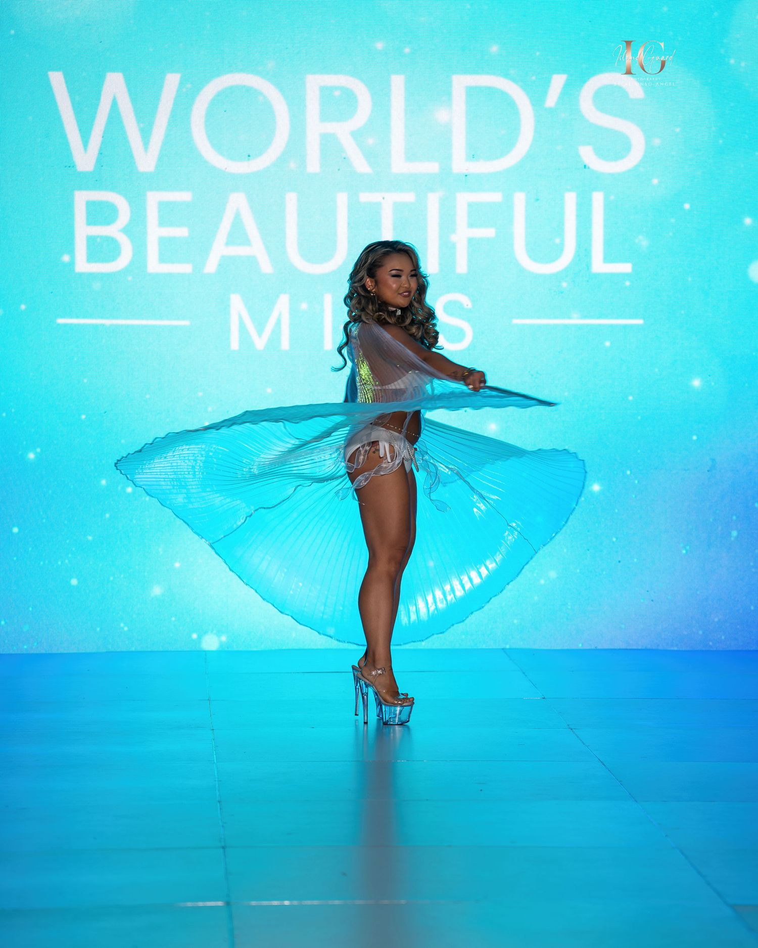 A model poses against a bright turquoise background with glowing text displaying 'WORLD'S BEAUTIFUL' in white letters.