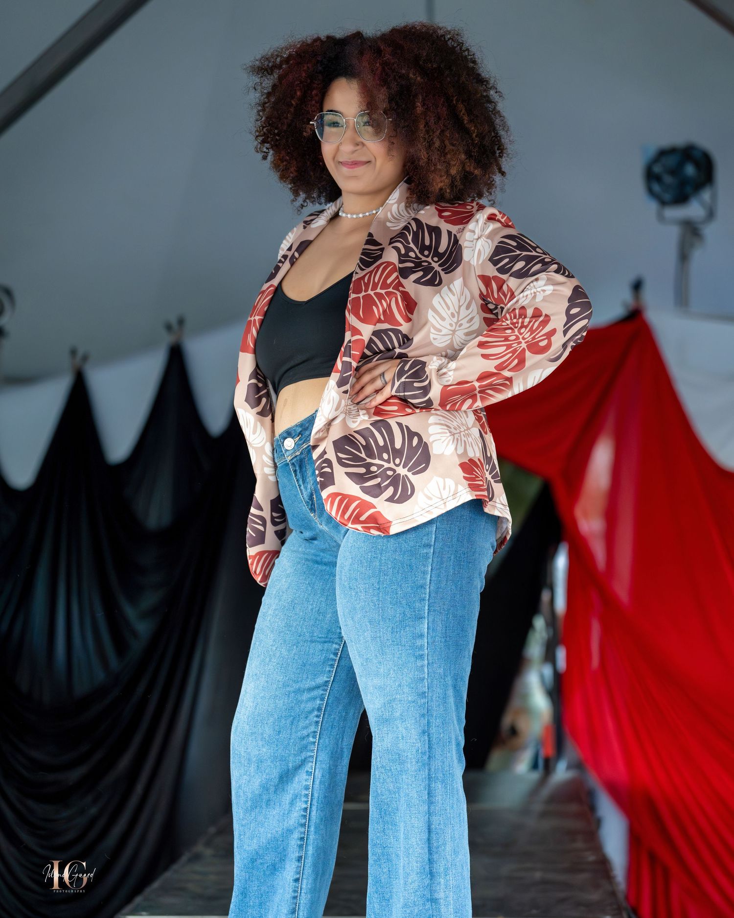 Models present tropical print blouses paired with blue jeans on runway.