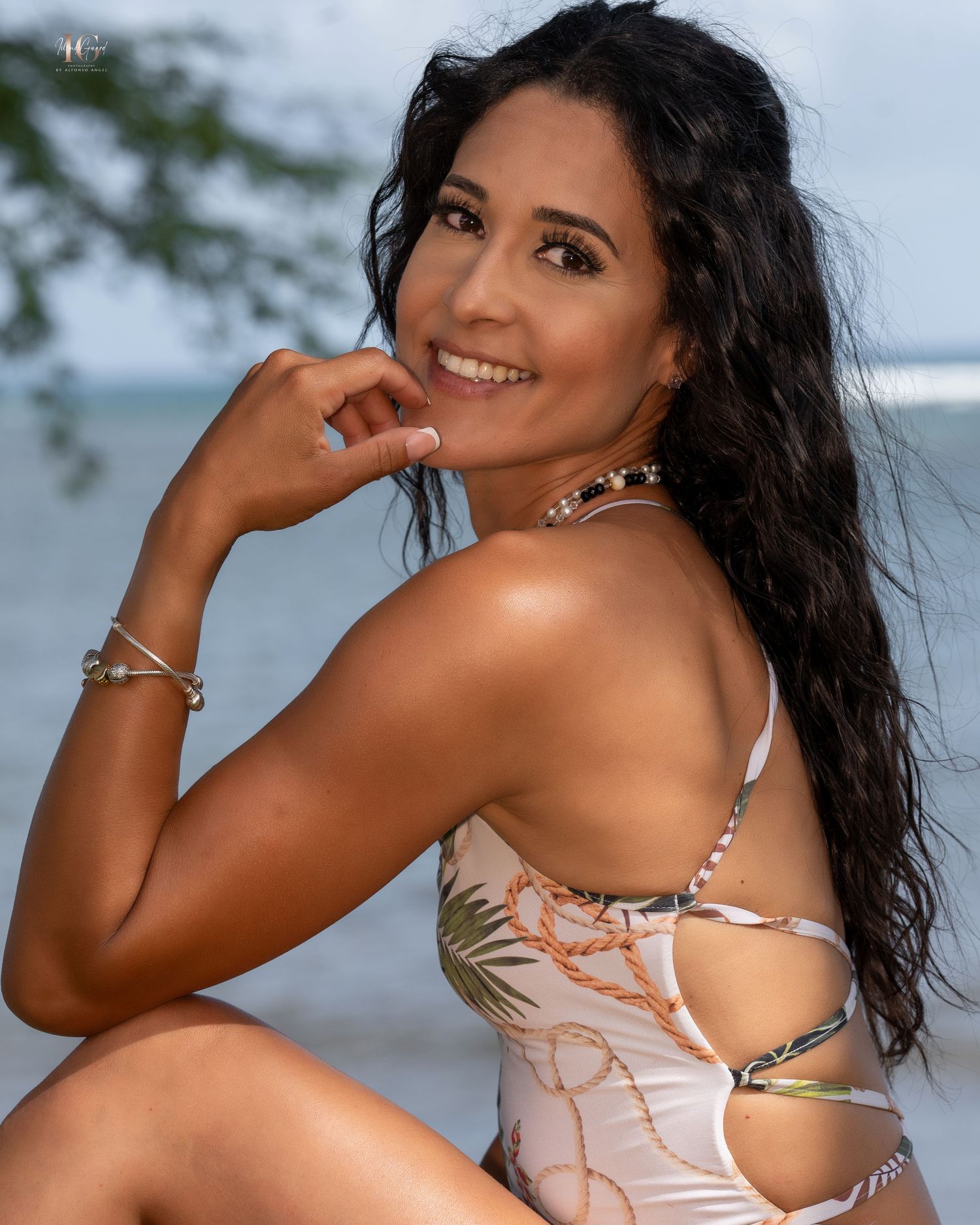 A person in a light colored swimsuit poses on a beach setting during a photoshoot session.