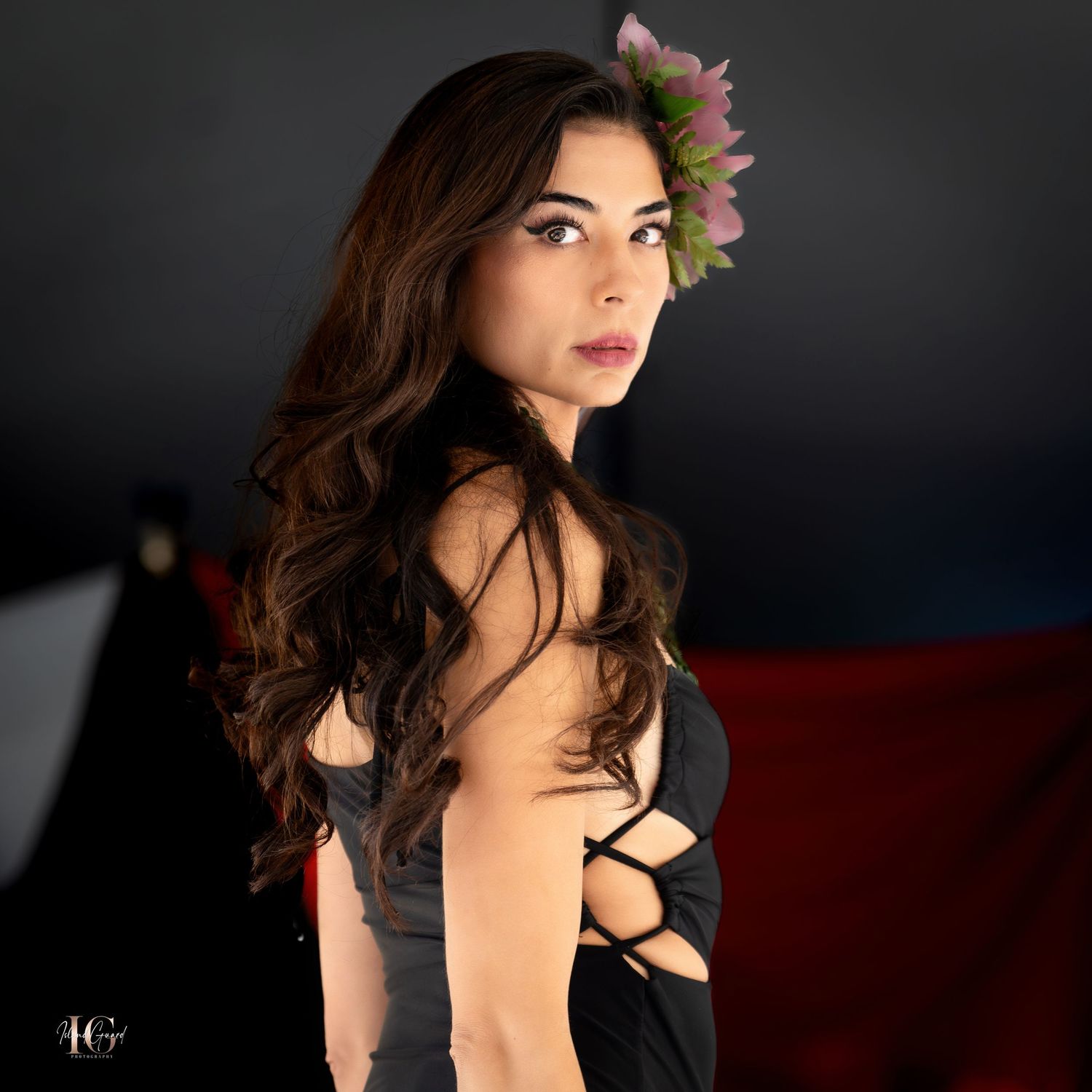 Artistic portrait with black dress and floral hair accessories against dark background.