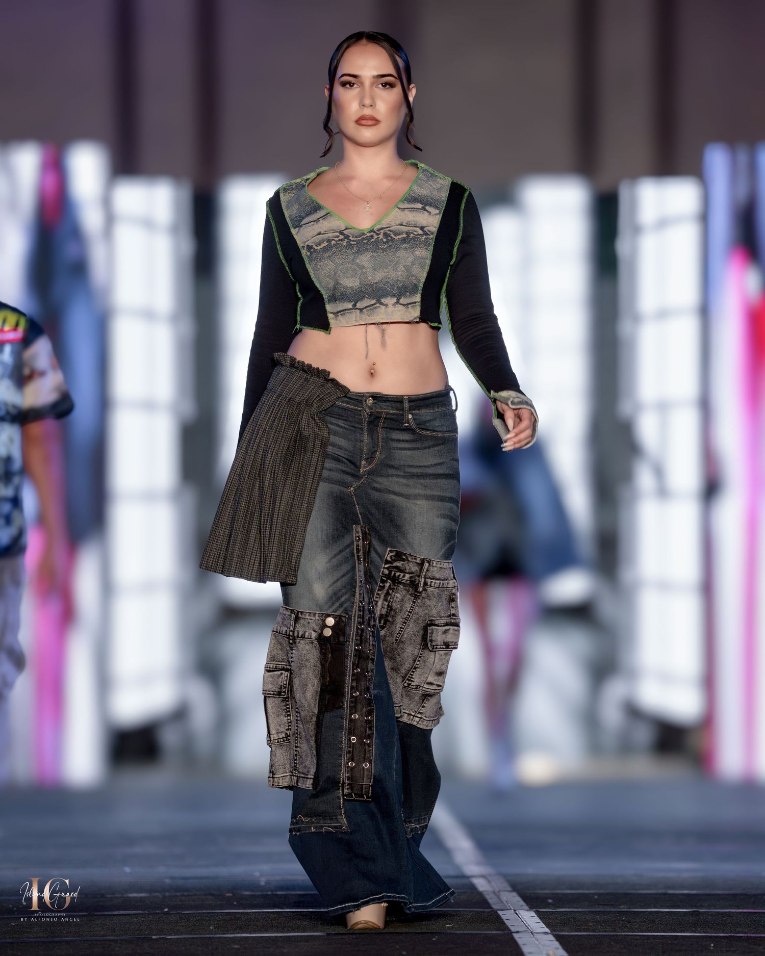 Model presents edgy streetwear look featuring cropped top and cargo pants on modern runway.