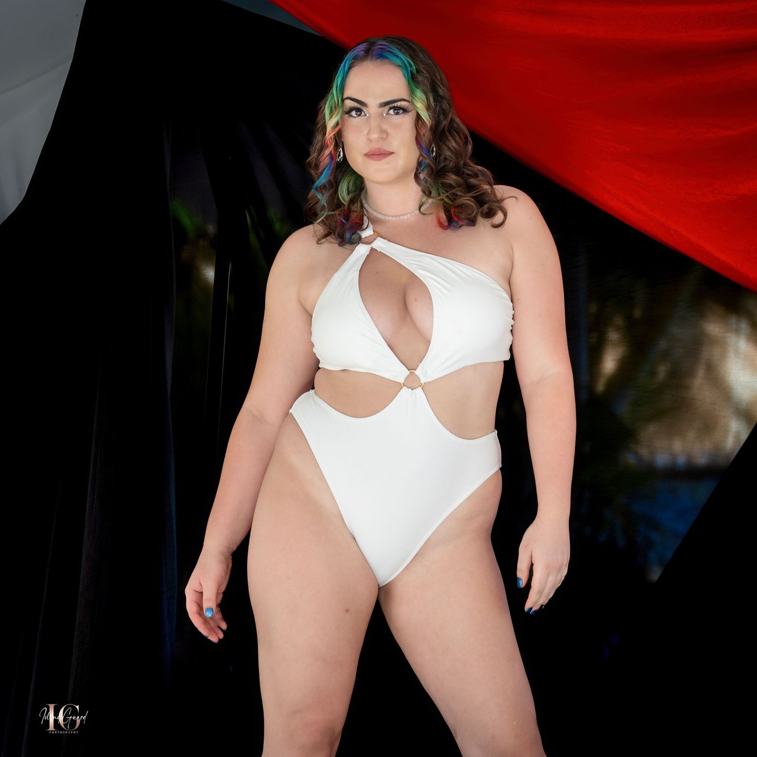 Model walking the catwalk in a white cutout swimsuit design.