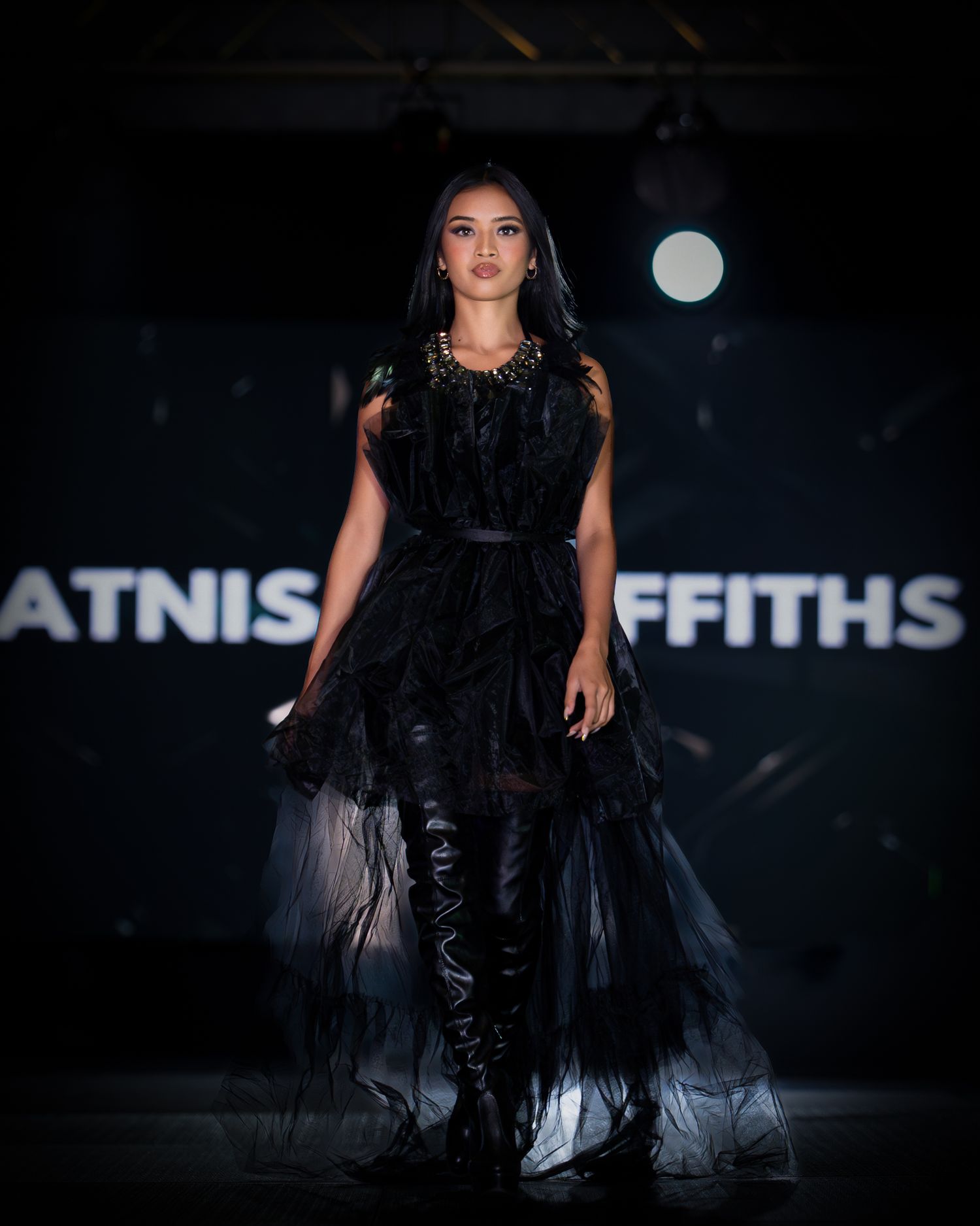 Fashion model walking runway in dramatic black gown during International Fashion Week.
