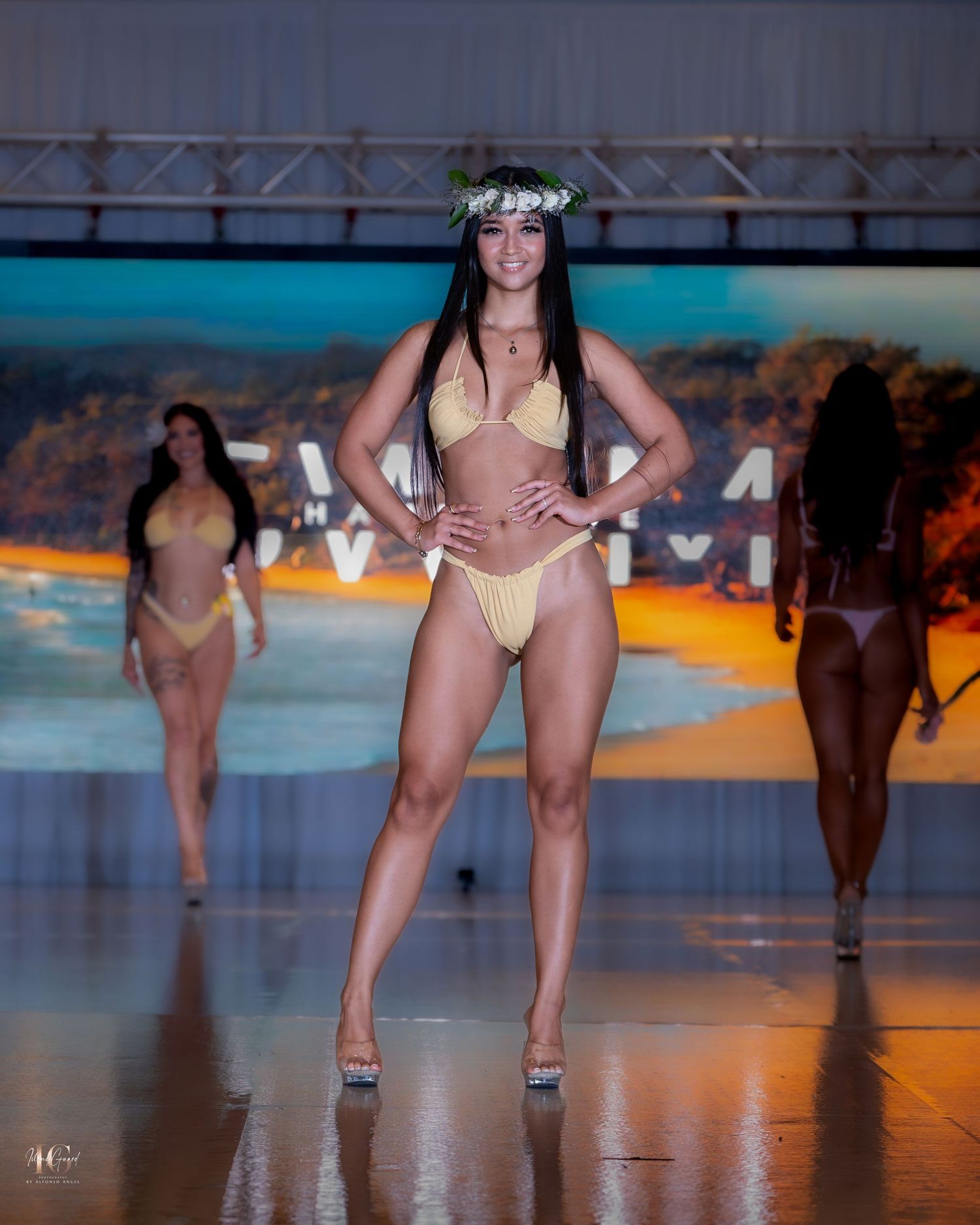 Models walk the runway in swimwear and floral headpieces during a tropical-themed fashion show.