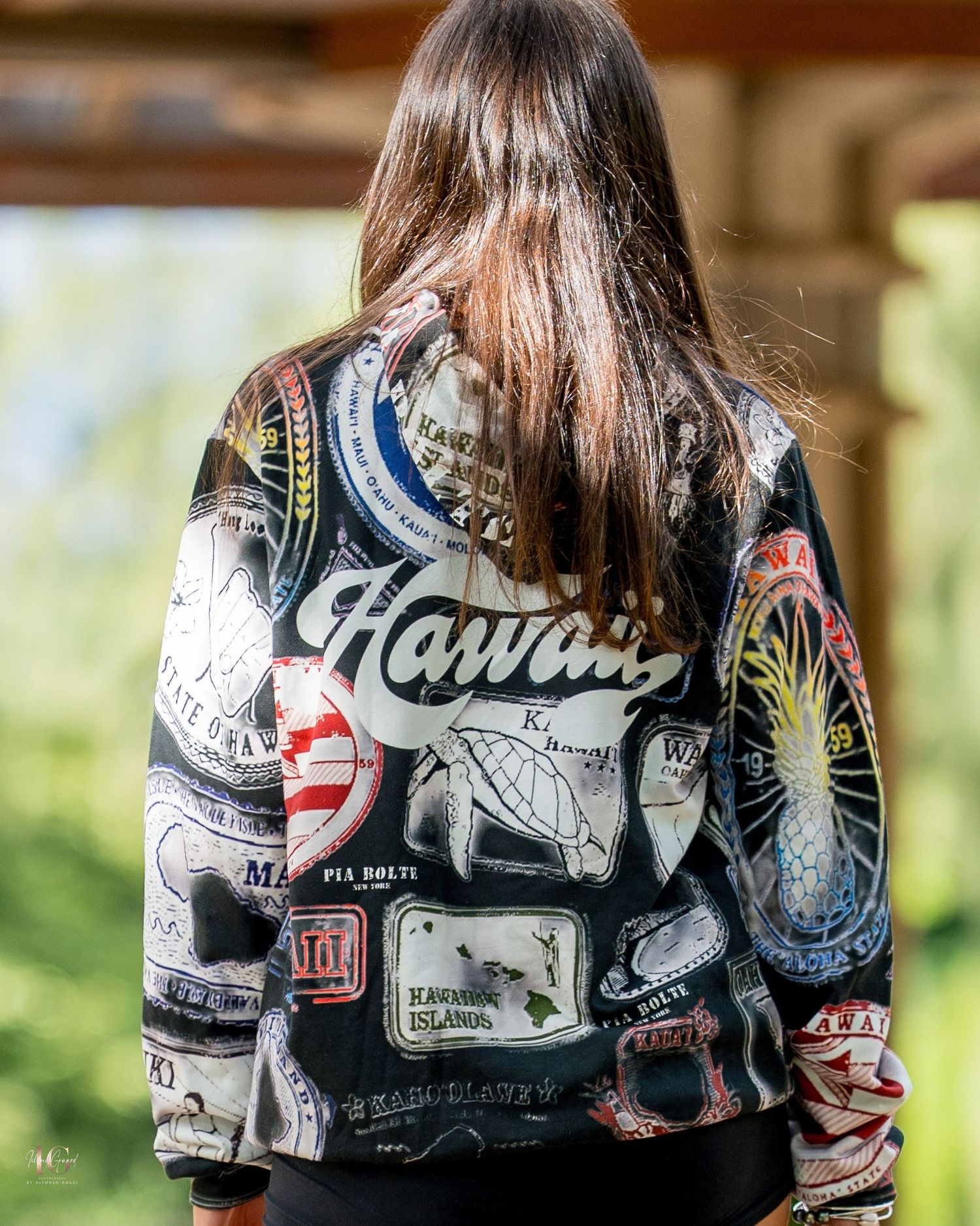 Back view of a leather jacket with Hawaii text and various patches and designs displayed against a blurred background.