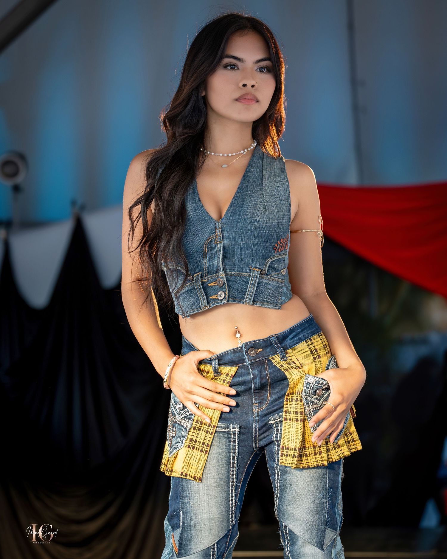 Denim vest and yellow plaid fashion ensemble on dimly lit catwalk.