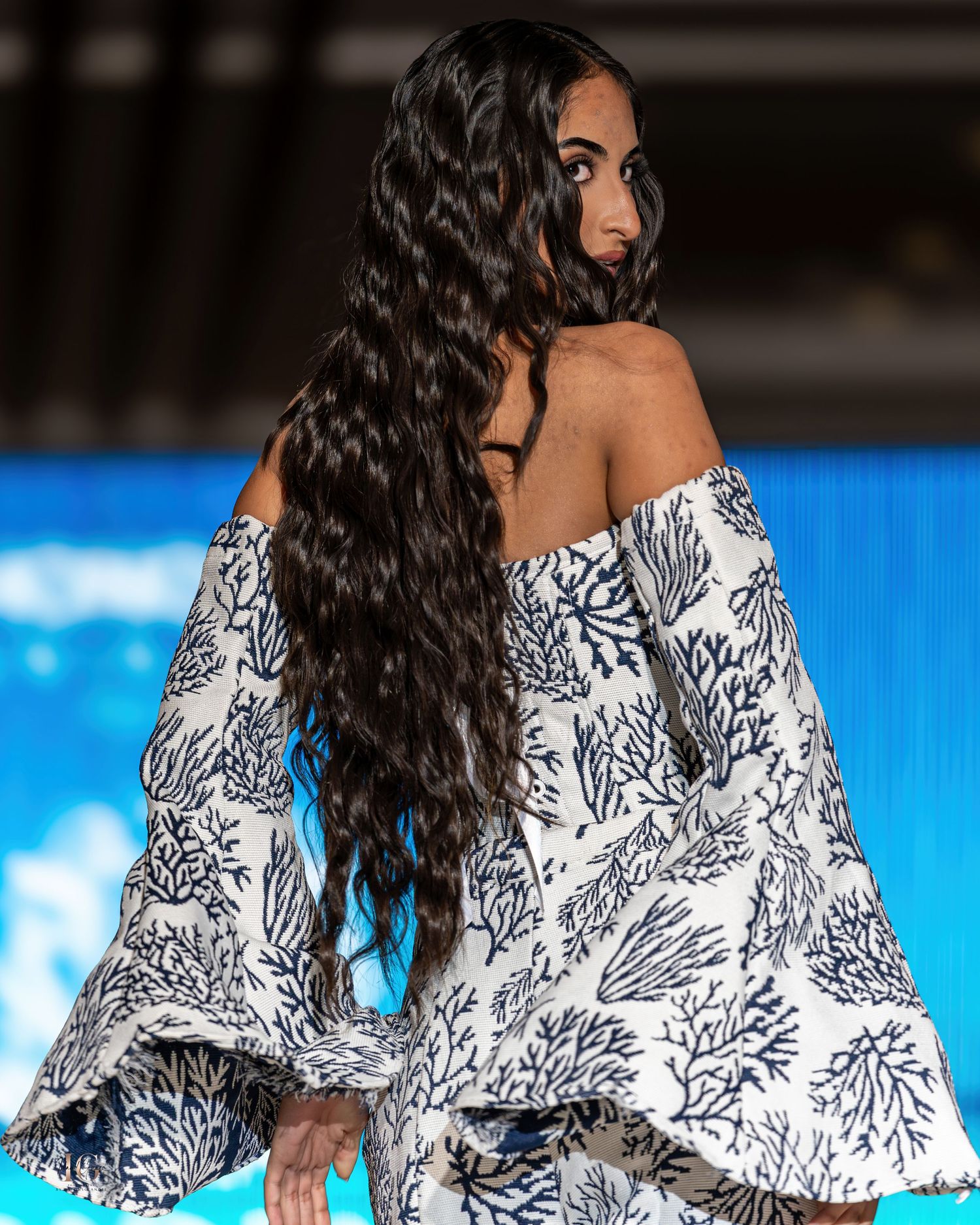Off-shoulder dress with dramatic black and white floral pattern swirls on catwalk at fashion show.