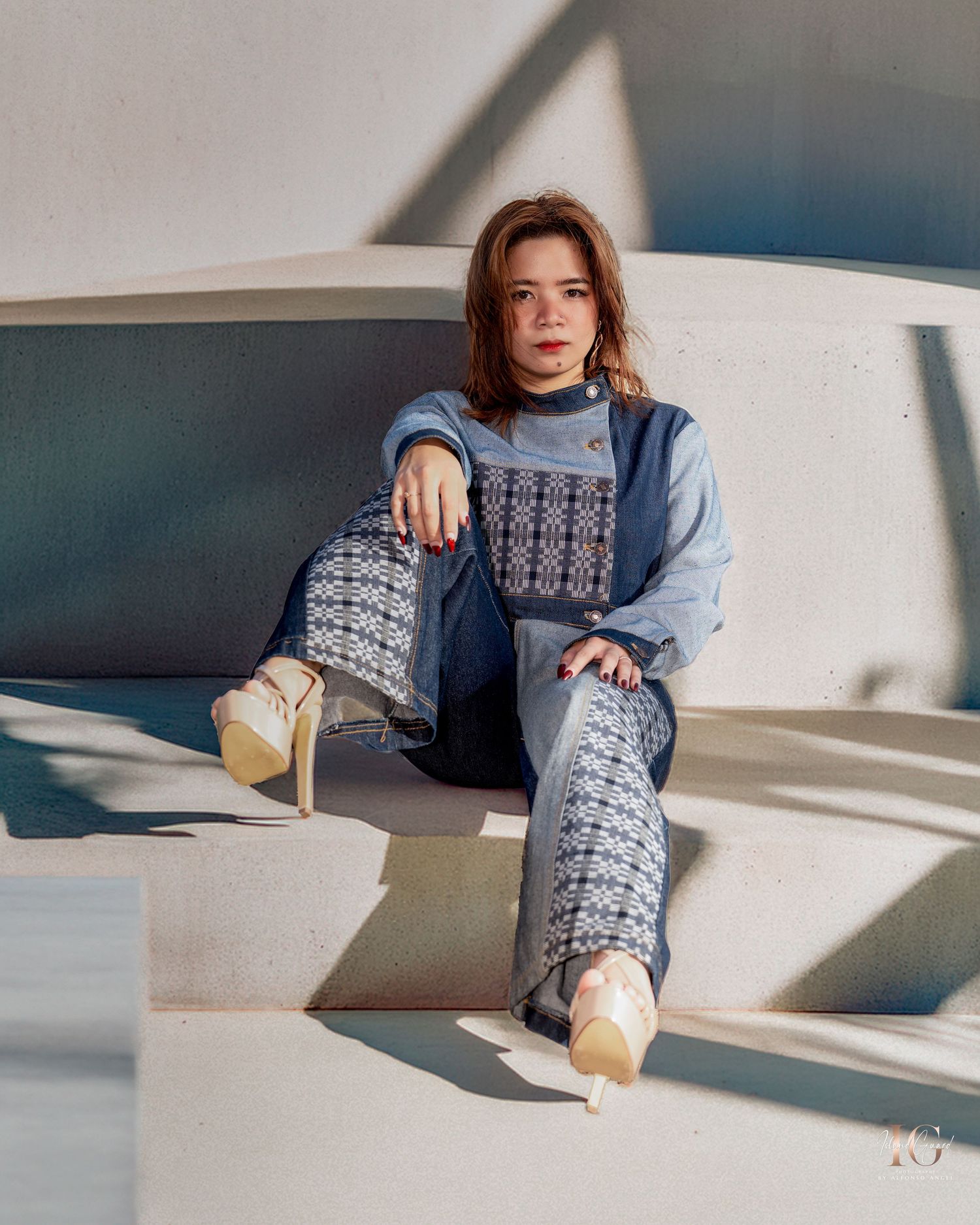 Person in casual denim and sweater lounging with sunlight casting shadows on white background.