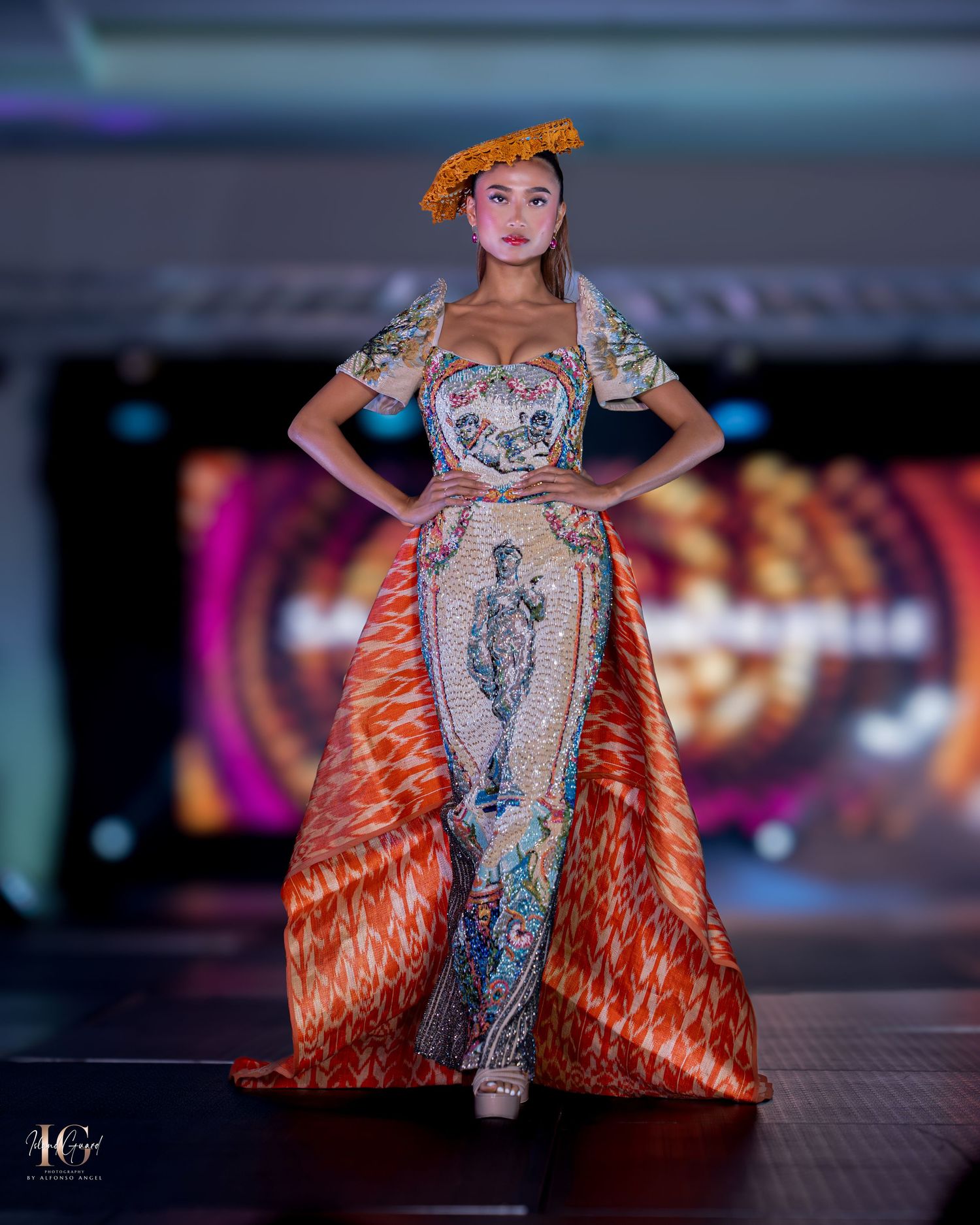 Avant-garde dress featuring printed panel and orange feathered overlay shown on fashion runway.