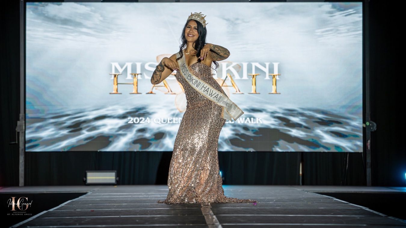 Model wearing a floral dress walks down an illuminated runway during a fashion show event.