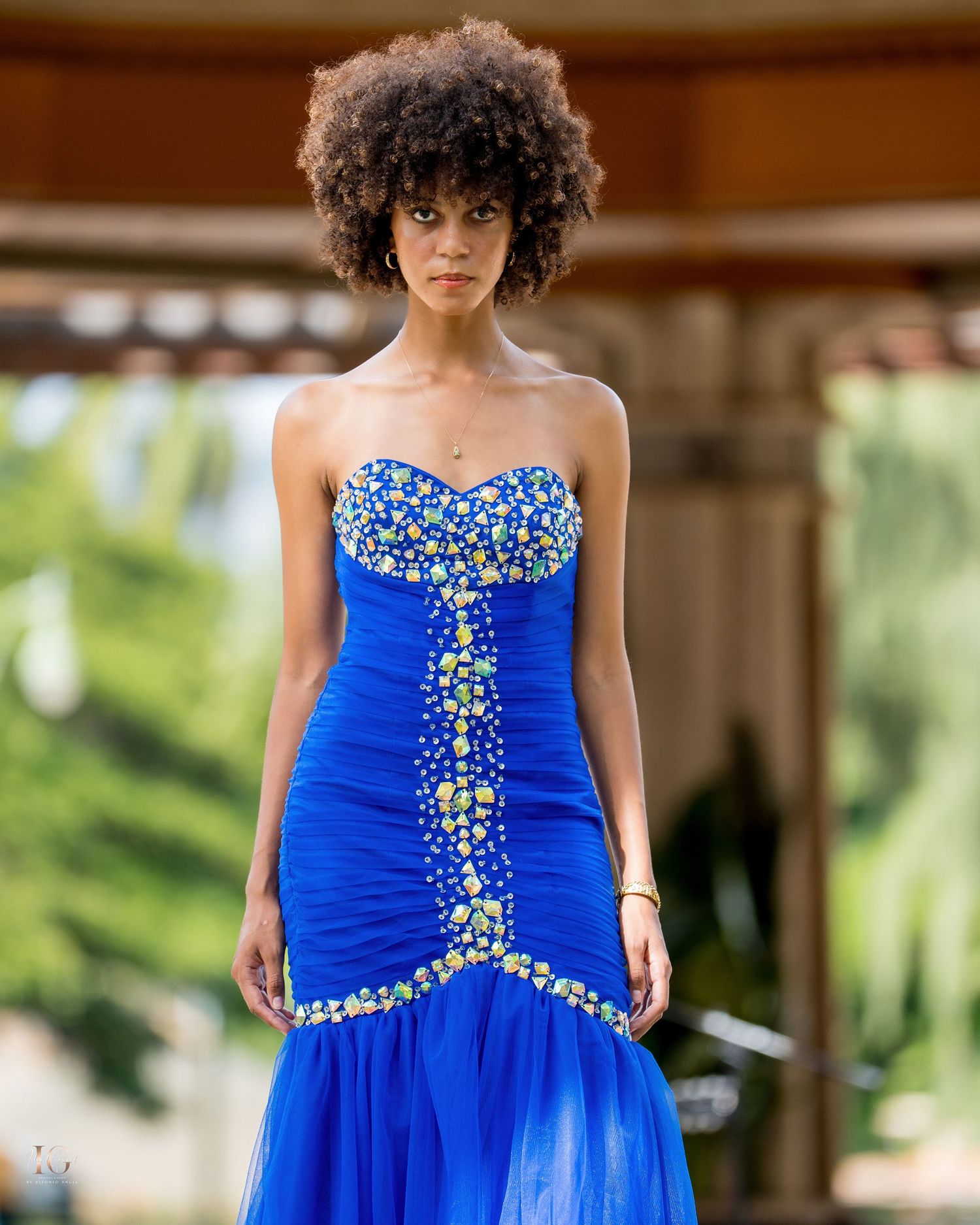 A model showcases a stunning royal blue prom dress with crystal embellishments and ruched detailing.