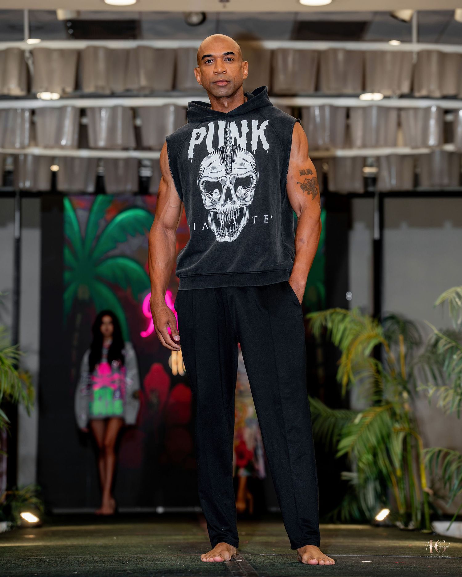 Person wearing a black tank top with skull design performs martial arts moves in an indoor training space.