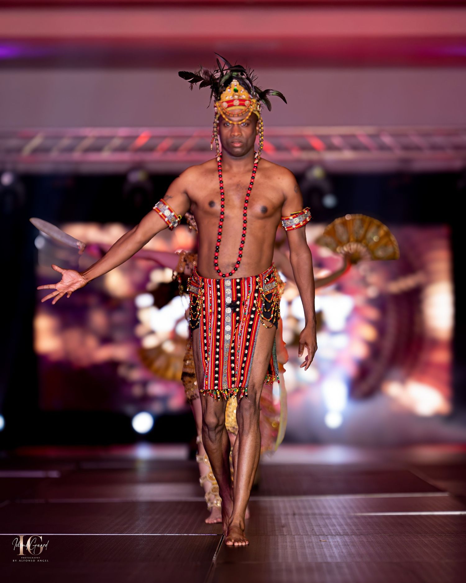Tribal-inspired runway look featuring traditional red and white patterns with feathered headdress.