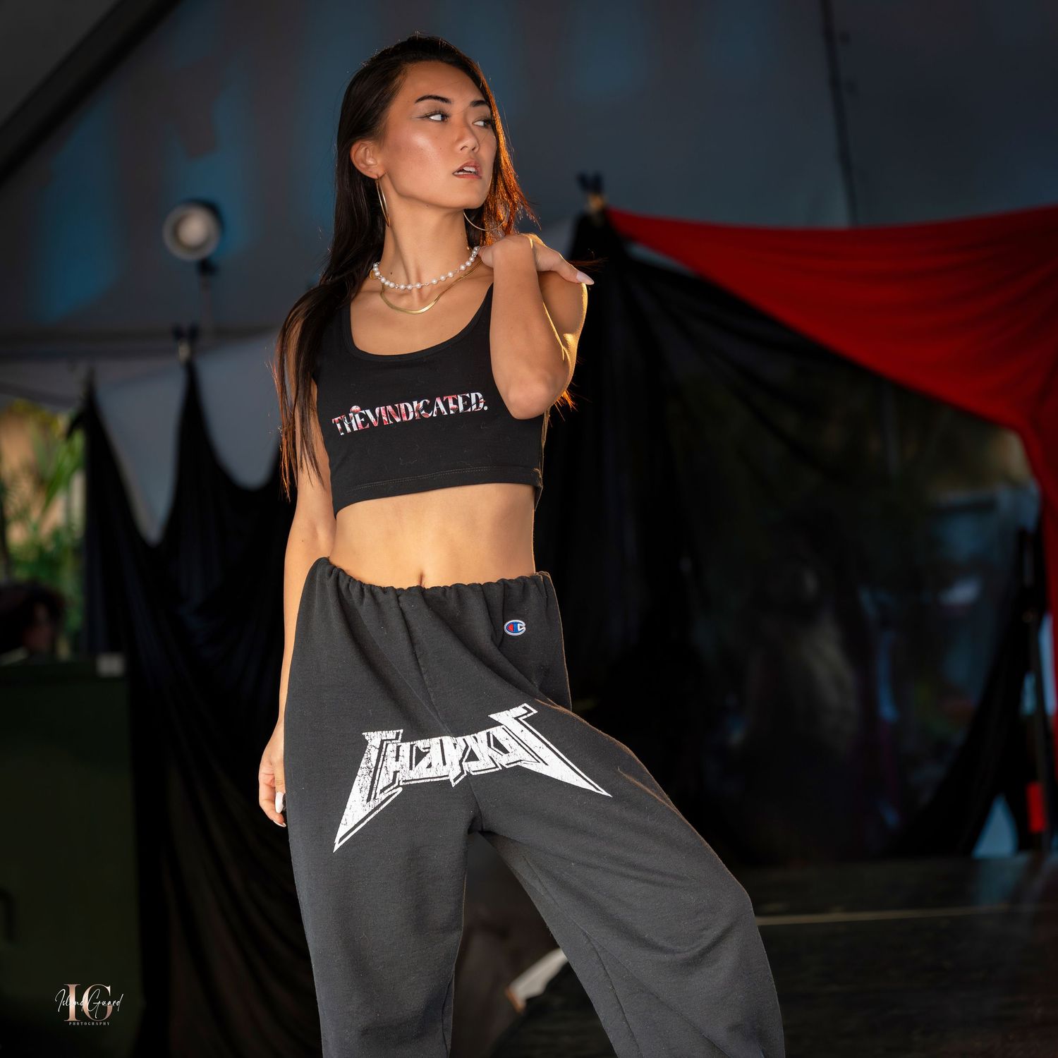 Model wearing black streetwear with graphic print on fashion catwalk.