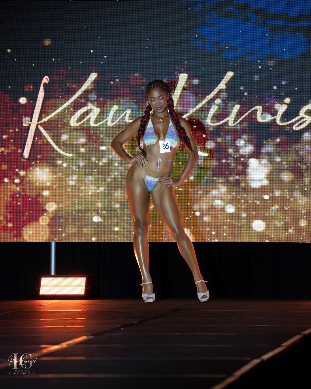 Fashion show runway with dramatic lighting and sparkly digital backdrop effects.