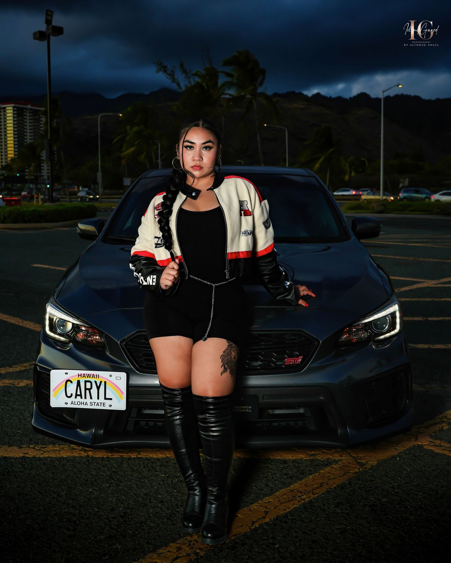 A sports car with LED headlights parked in a dark parking lot with city lights and palm trees in the background.