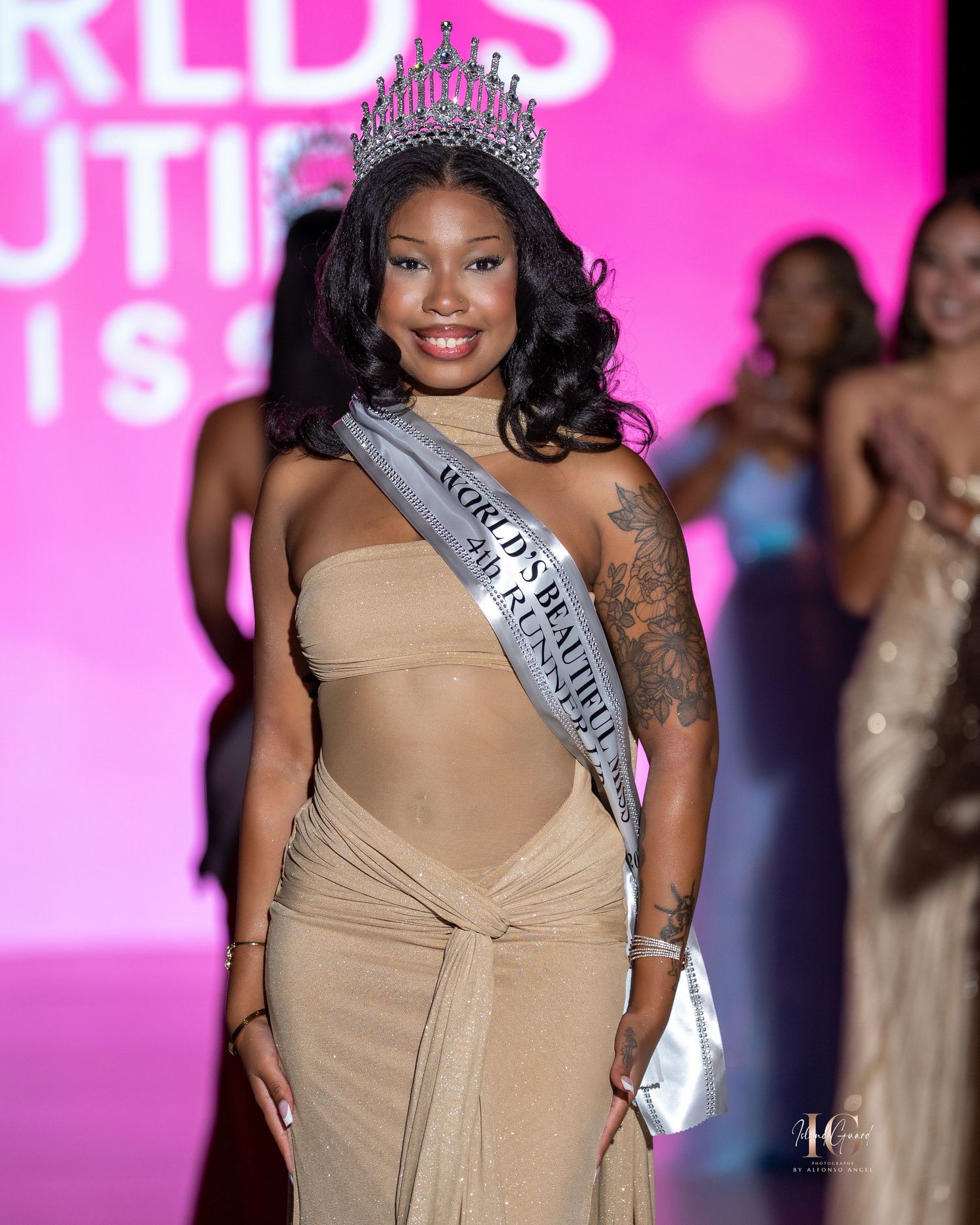 Contestants walk the runway at a beauty pageant event with pink lighting and decorative backdrop.