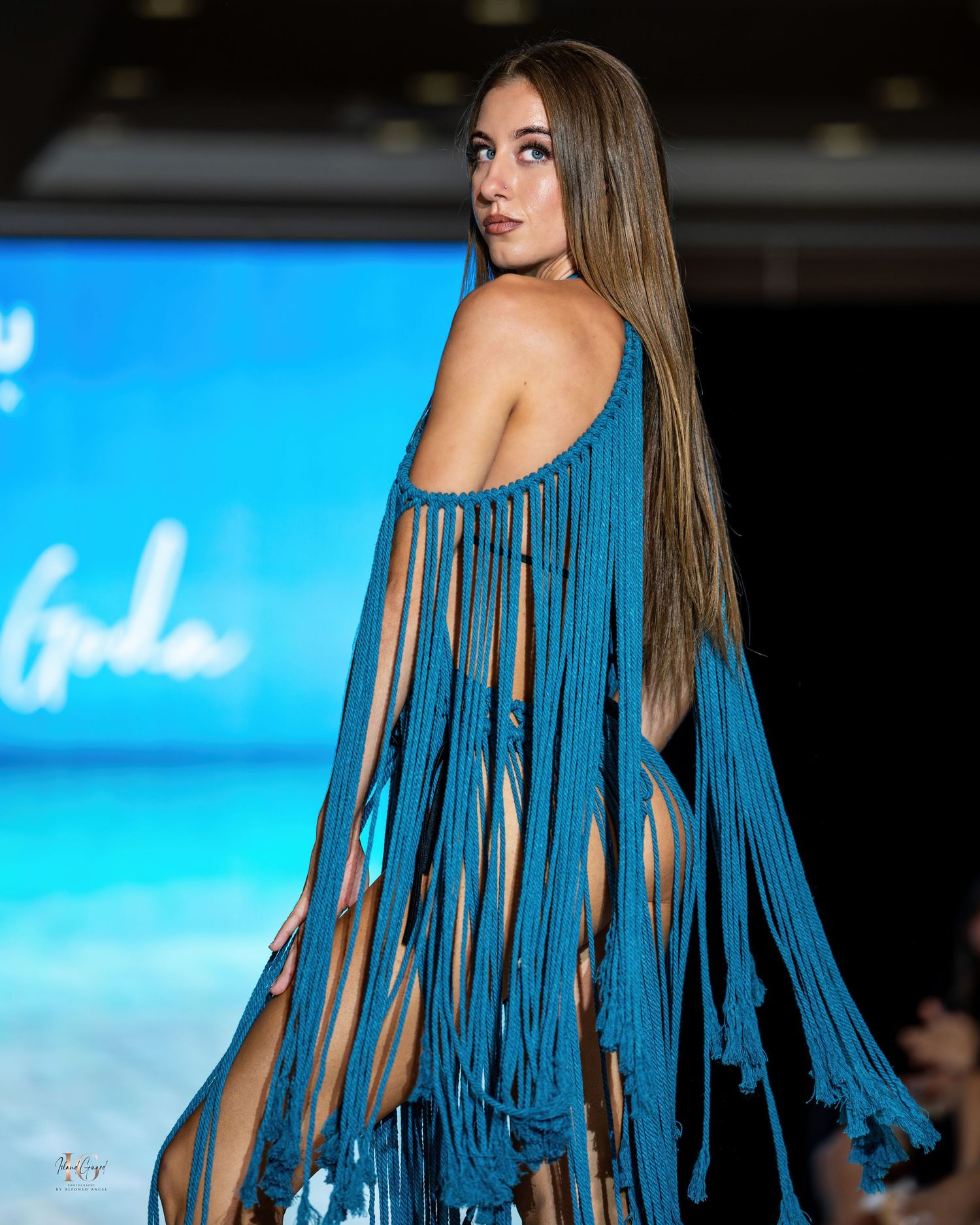 Dramatic blue fringe cover-up and swimwear ensemble presented at beach fashion show.
