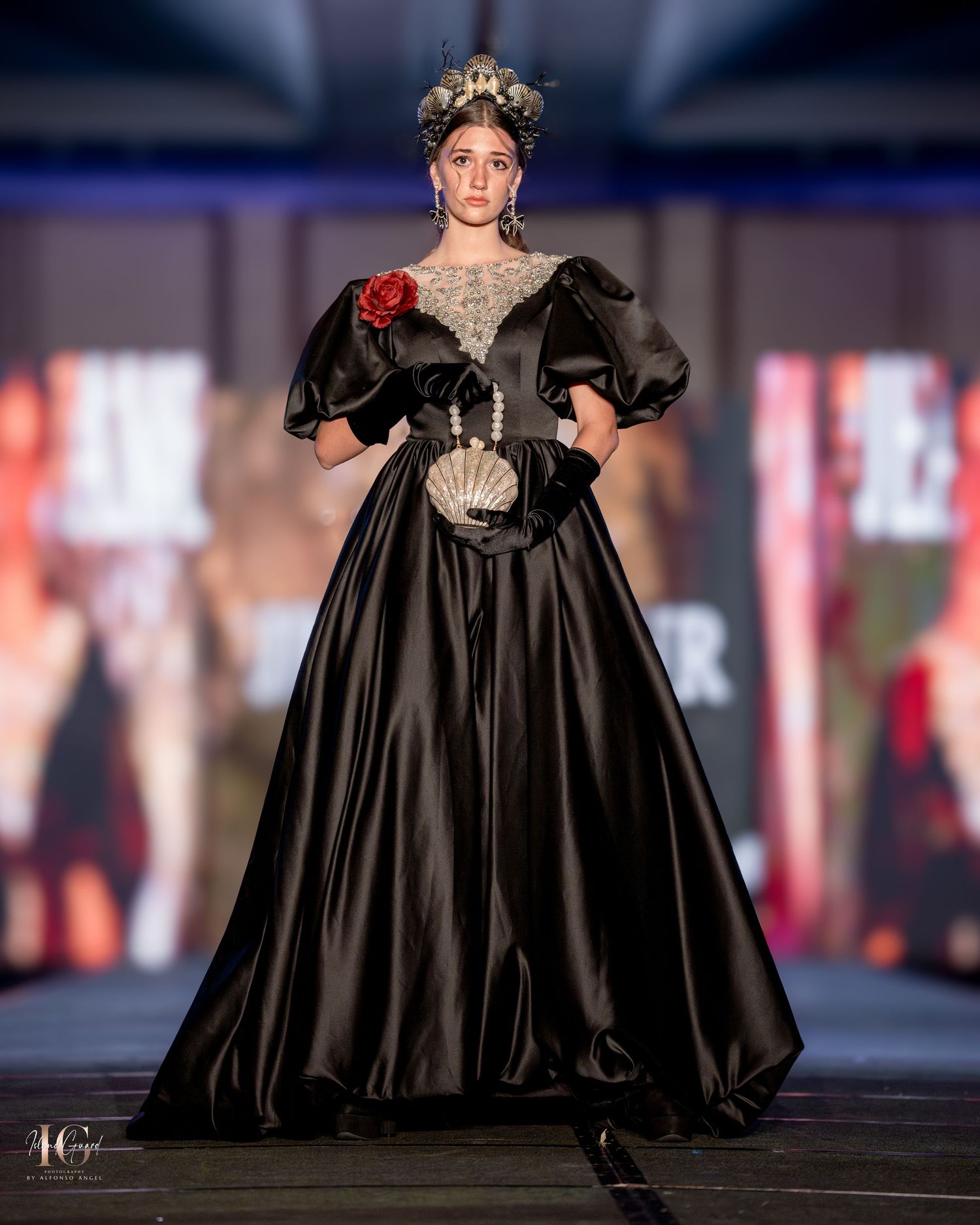 Dramatic black ballgown with puff sleeves and corset detail shown on illuminated runway.